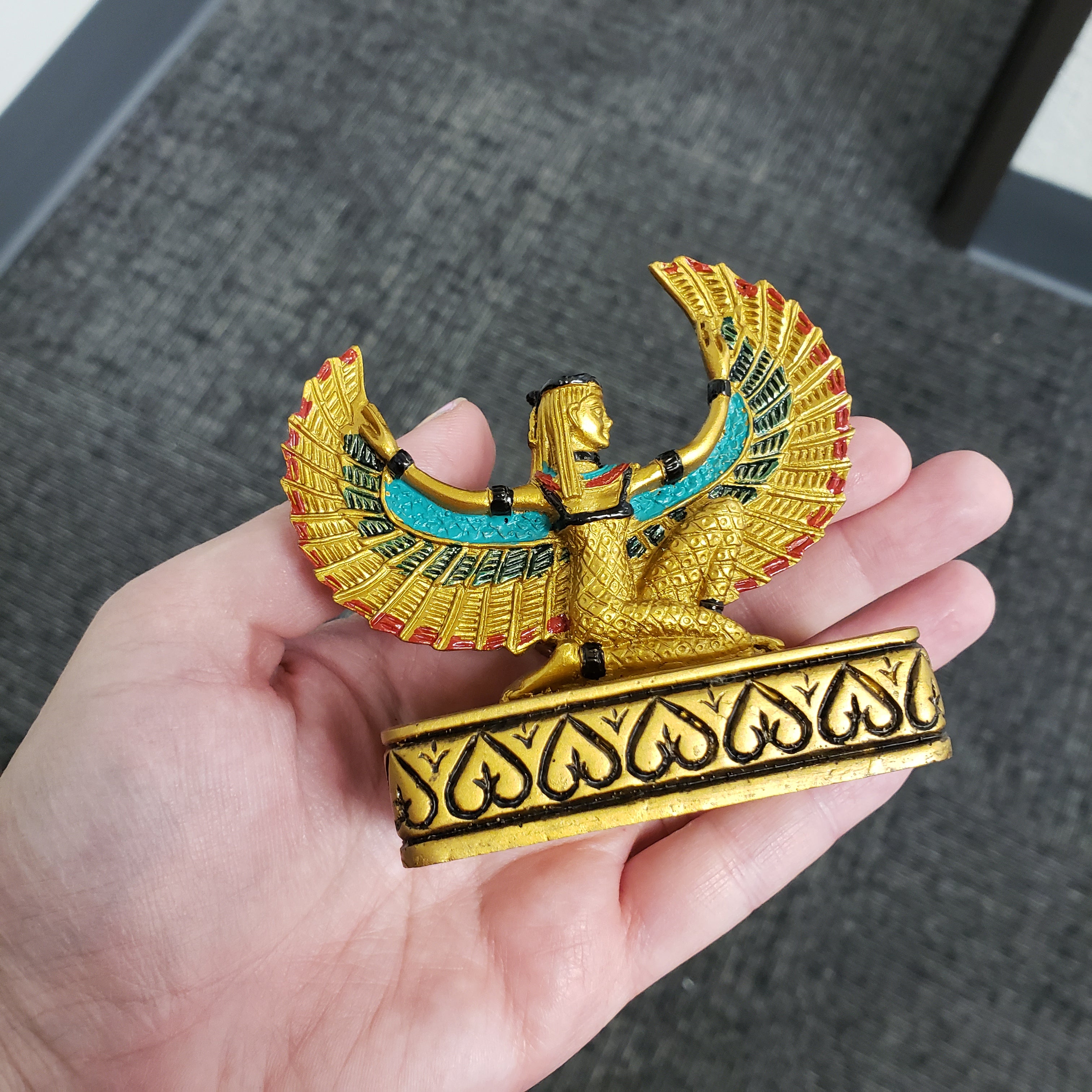 Decorative statue with Egyptian-style design held in a hand.
