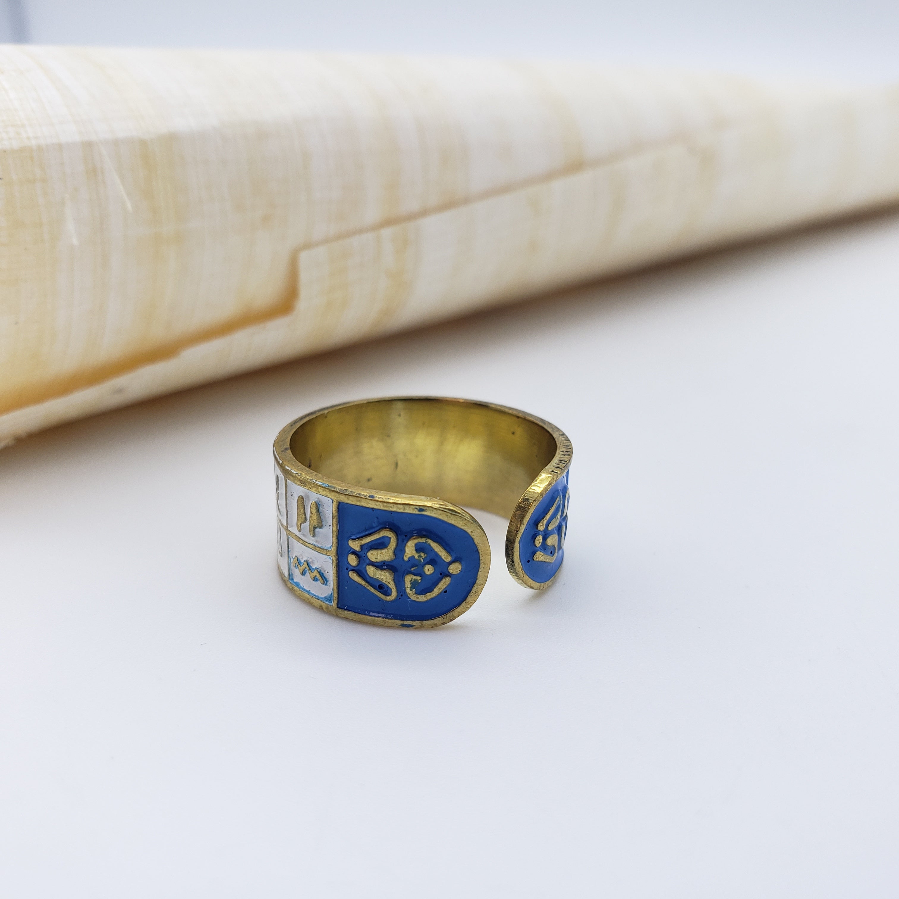 Gold ring with blue engraving on a white surface