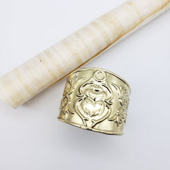 Gold ring with intricate design on a light gray background