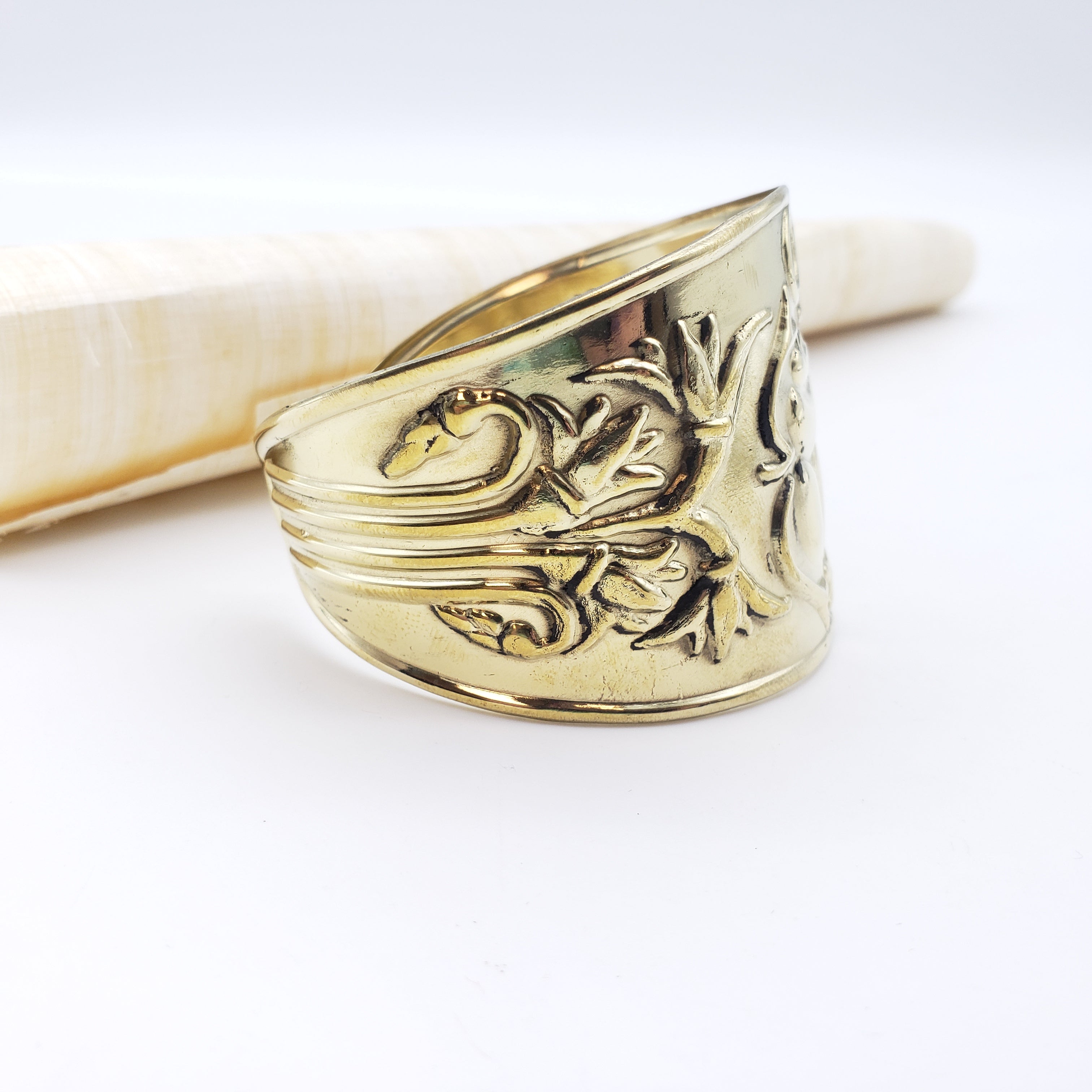 Gold ring with intricate design on a white background