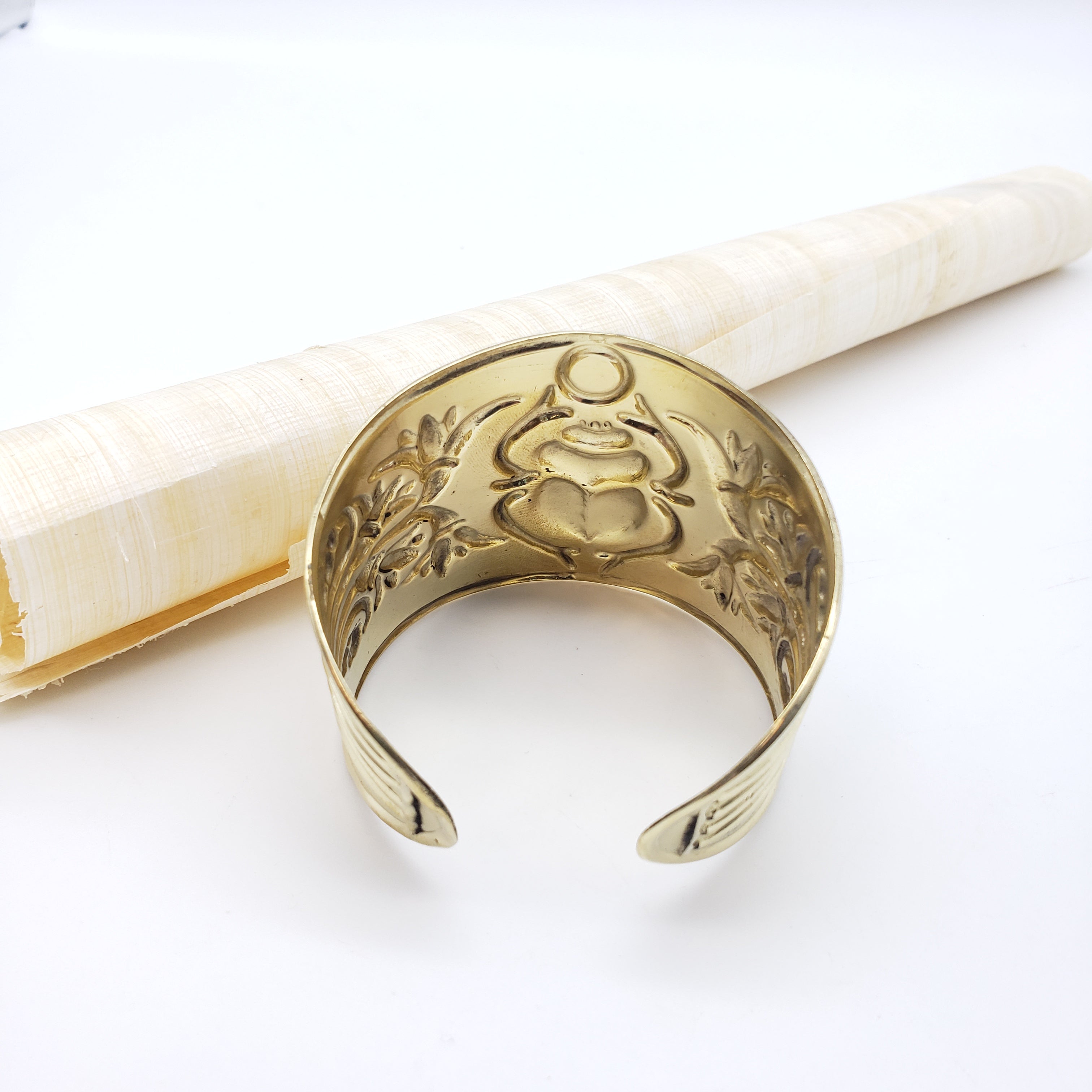 Gold crescent moon-shaped bracelet with intricate designs on a white background