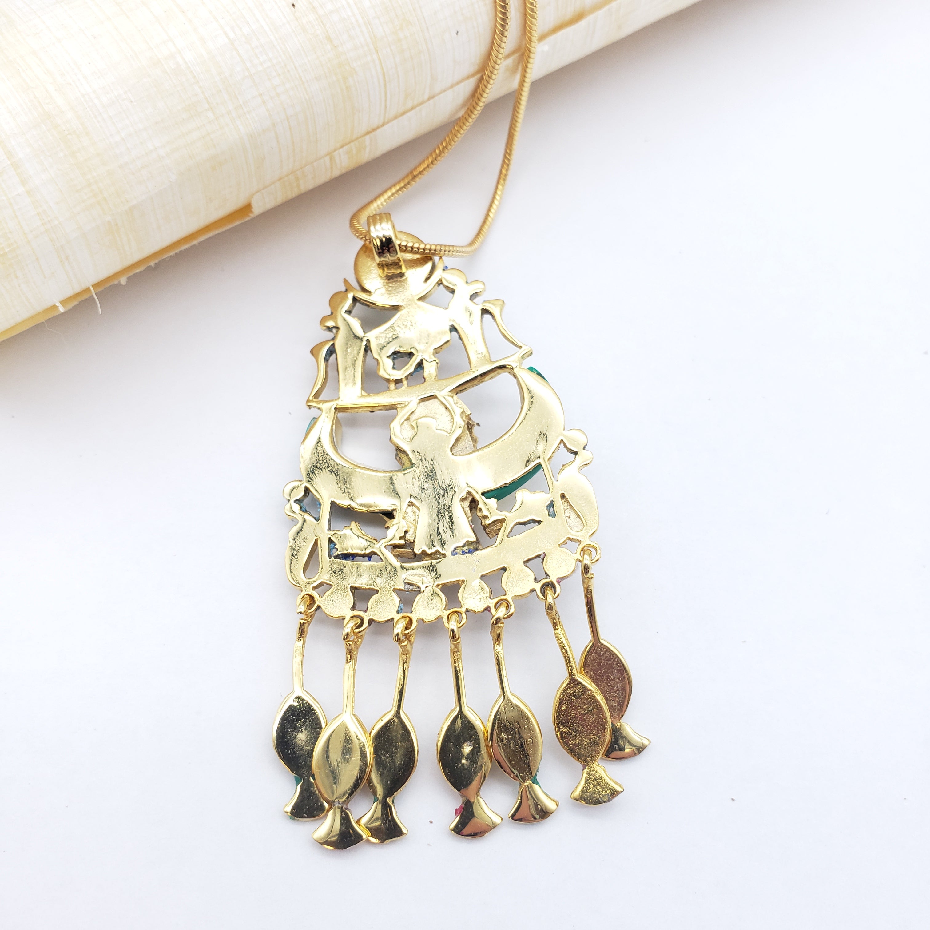 Gold necklace with a detailed pendant on a white background