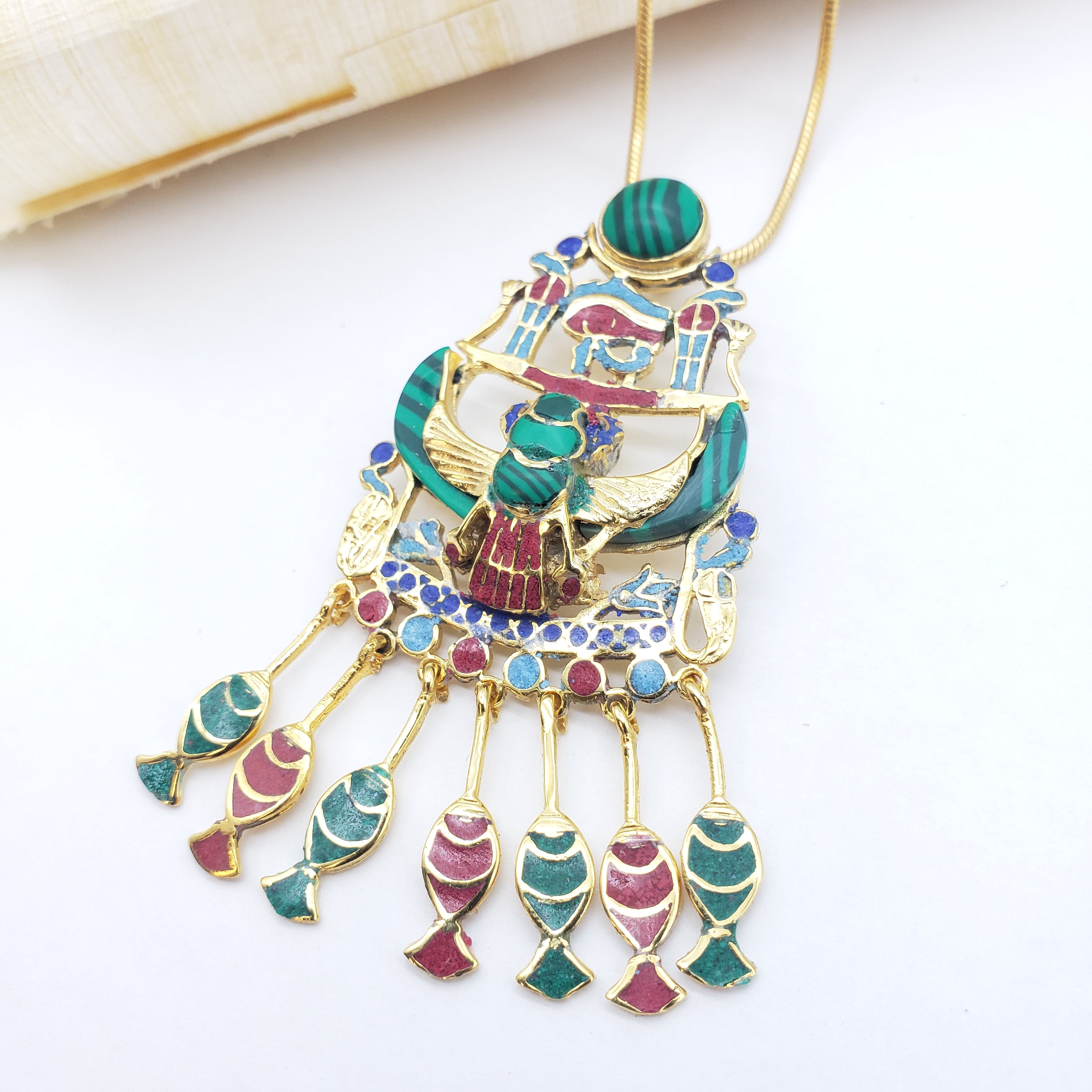 Colorful pendant with gold and gemstone details on a white background
