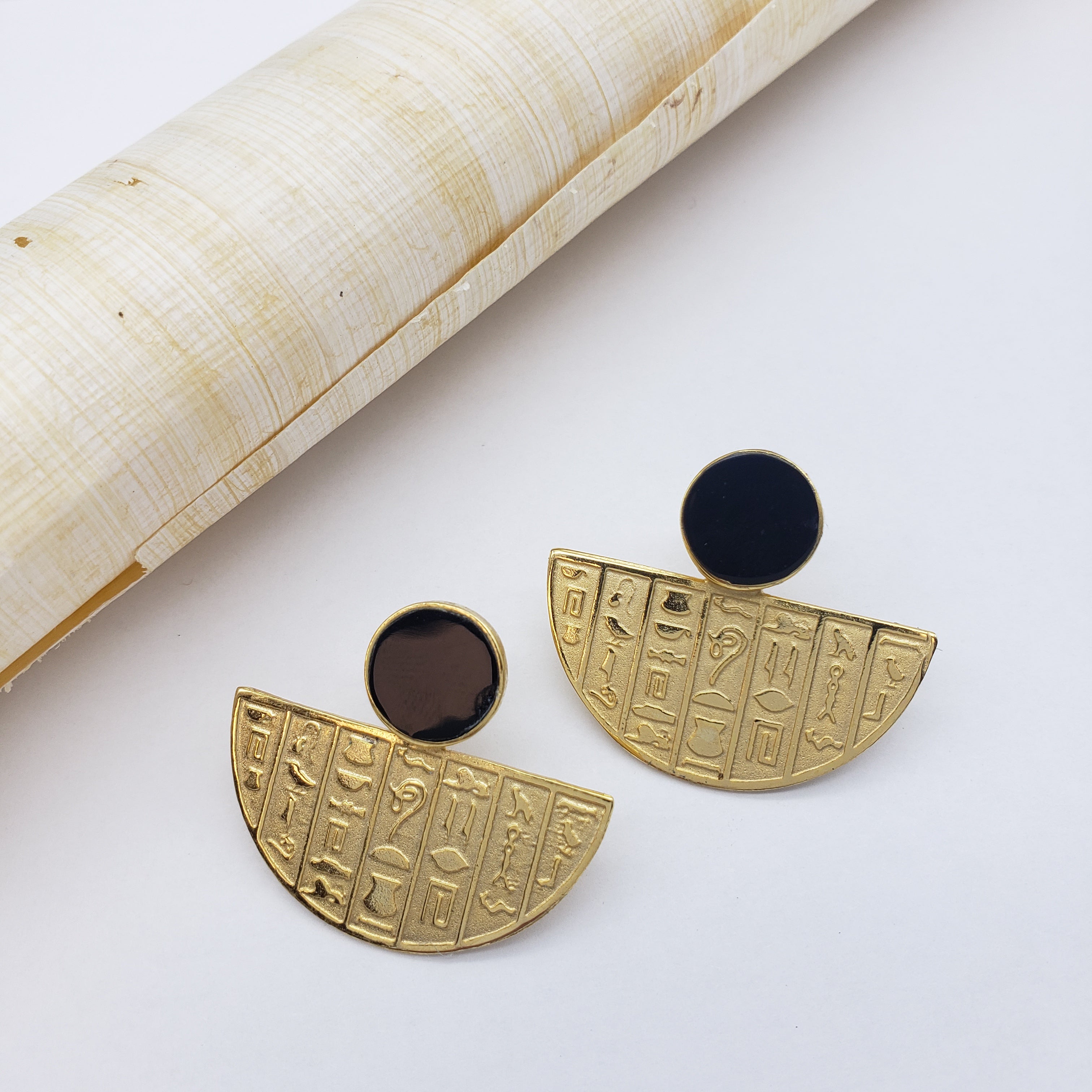 Gold earrings with hieroglyphic designs on a white background