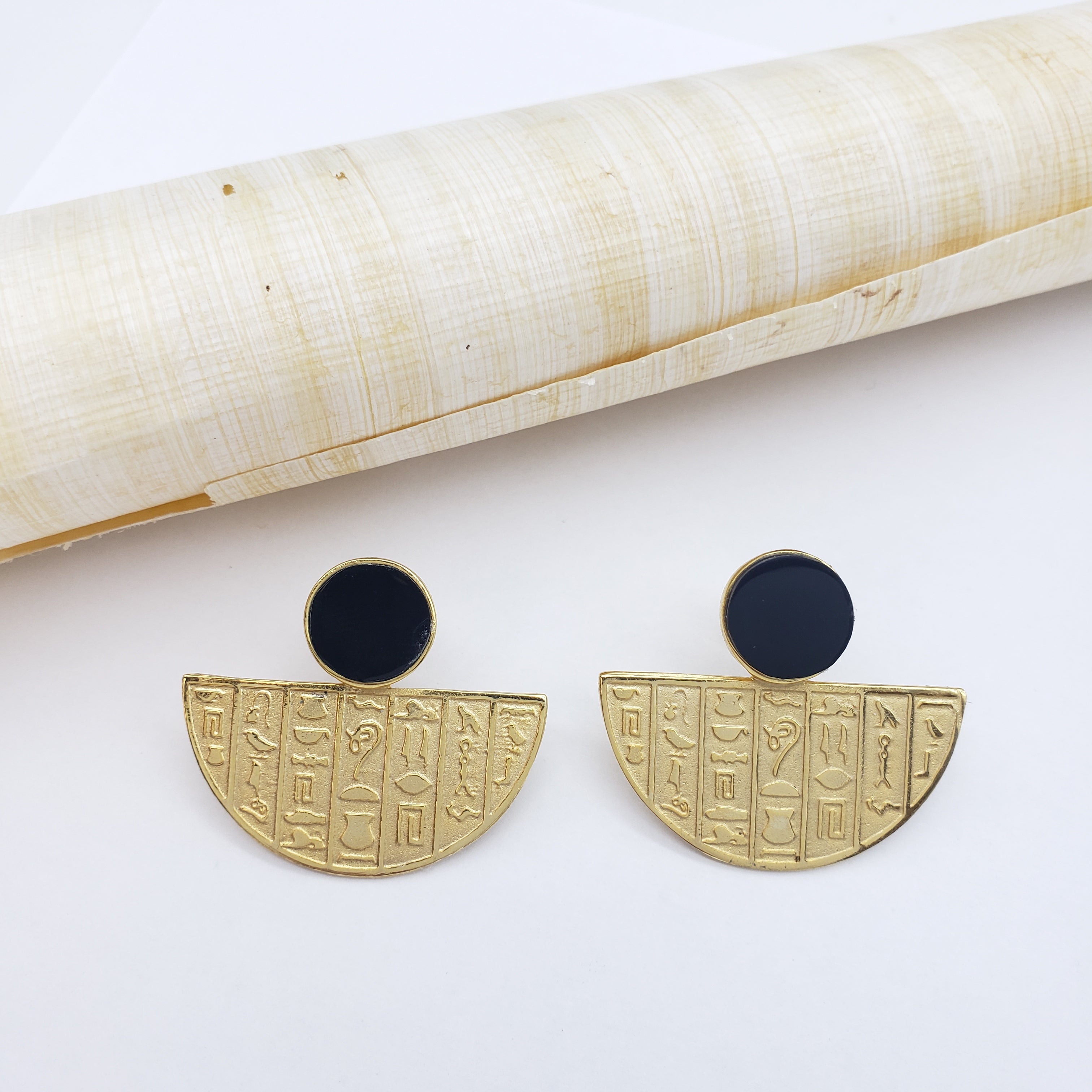 Gold earrings with black centers on a white background