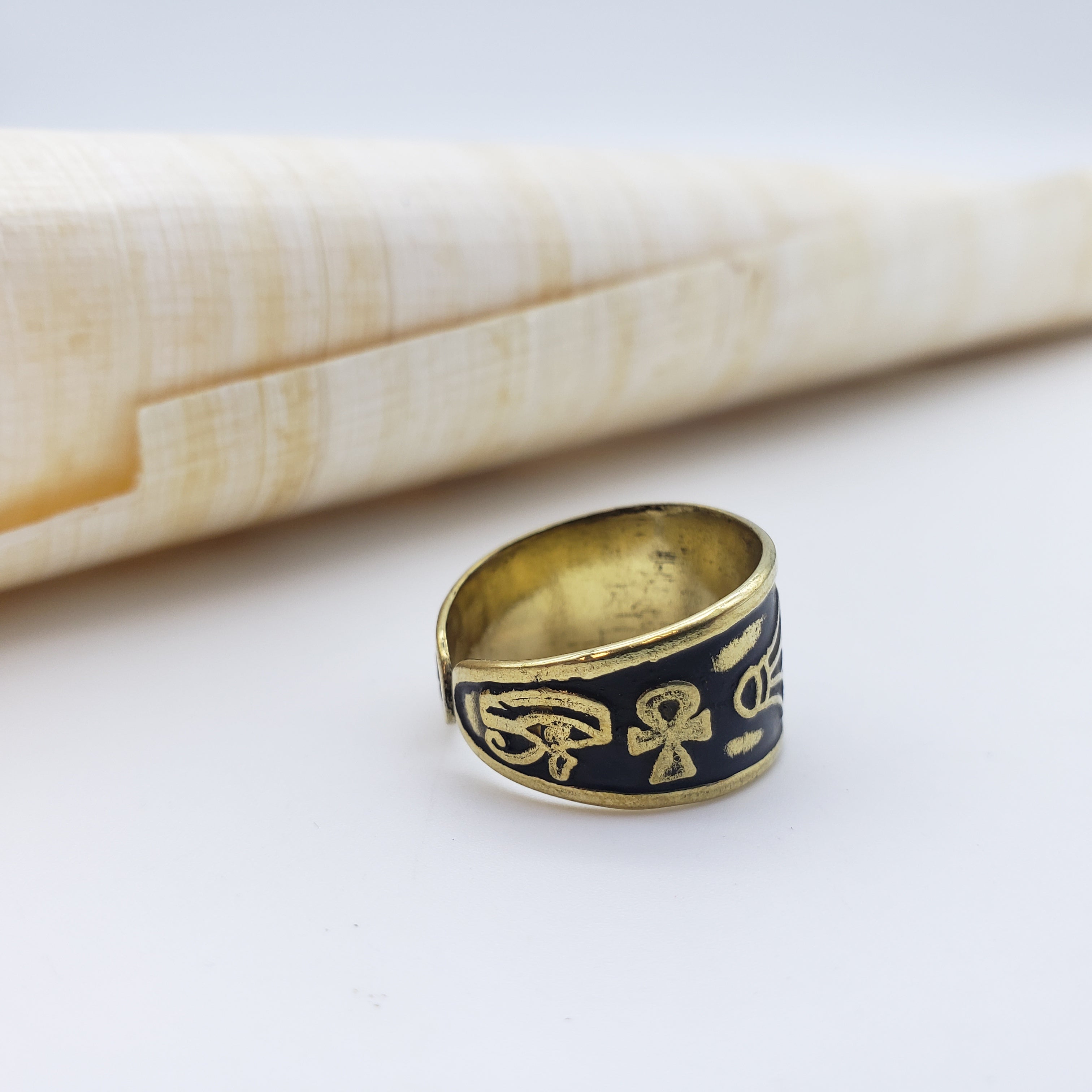 Gold and black ring with intricate design on a white surface