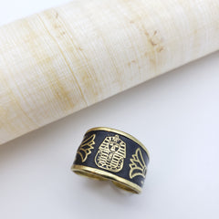Gold and black ring with intricate design on a white background