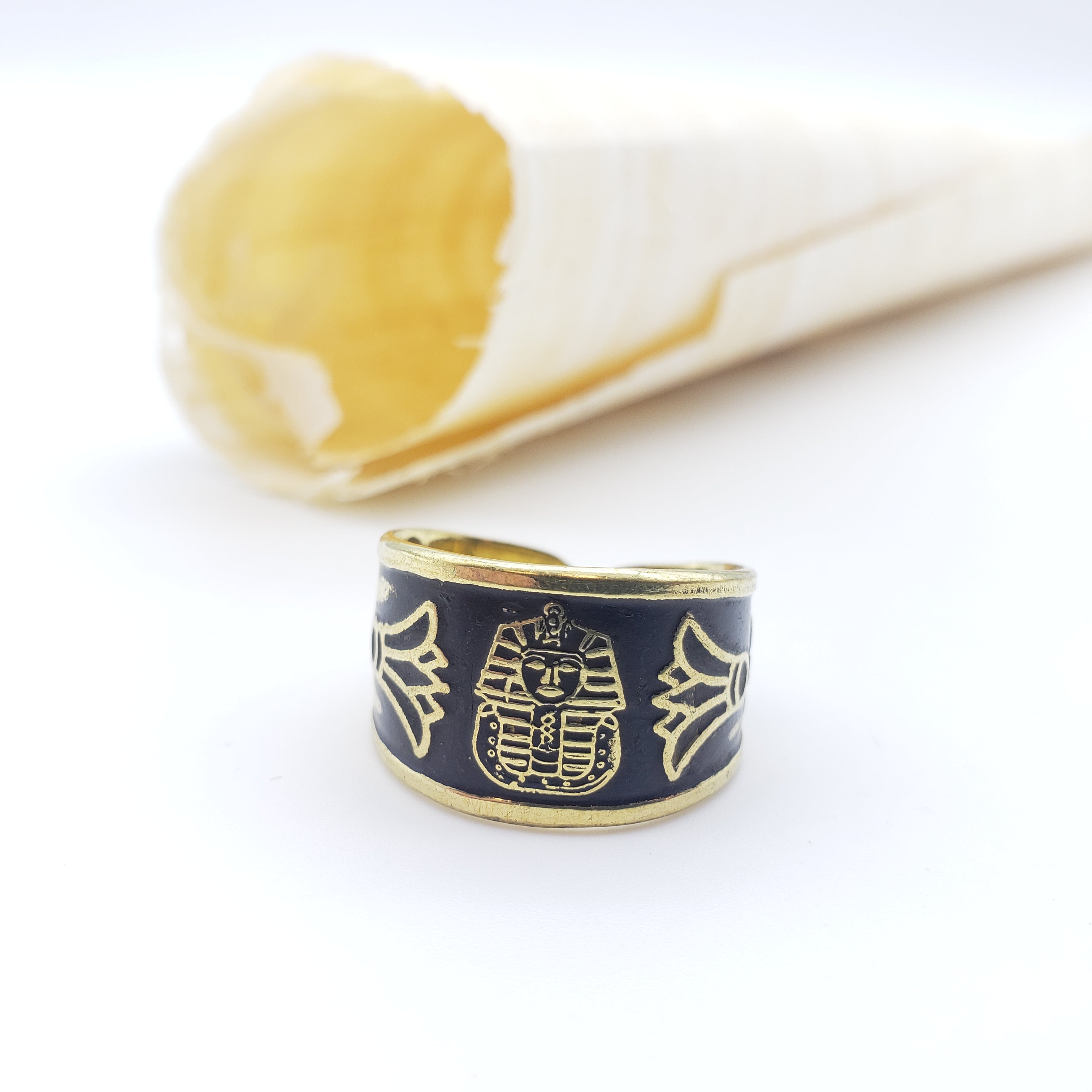 Gold and black ring with pharaoh design on a white background