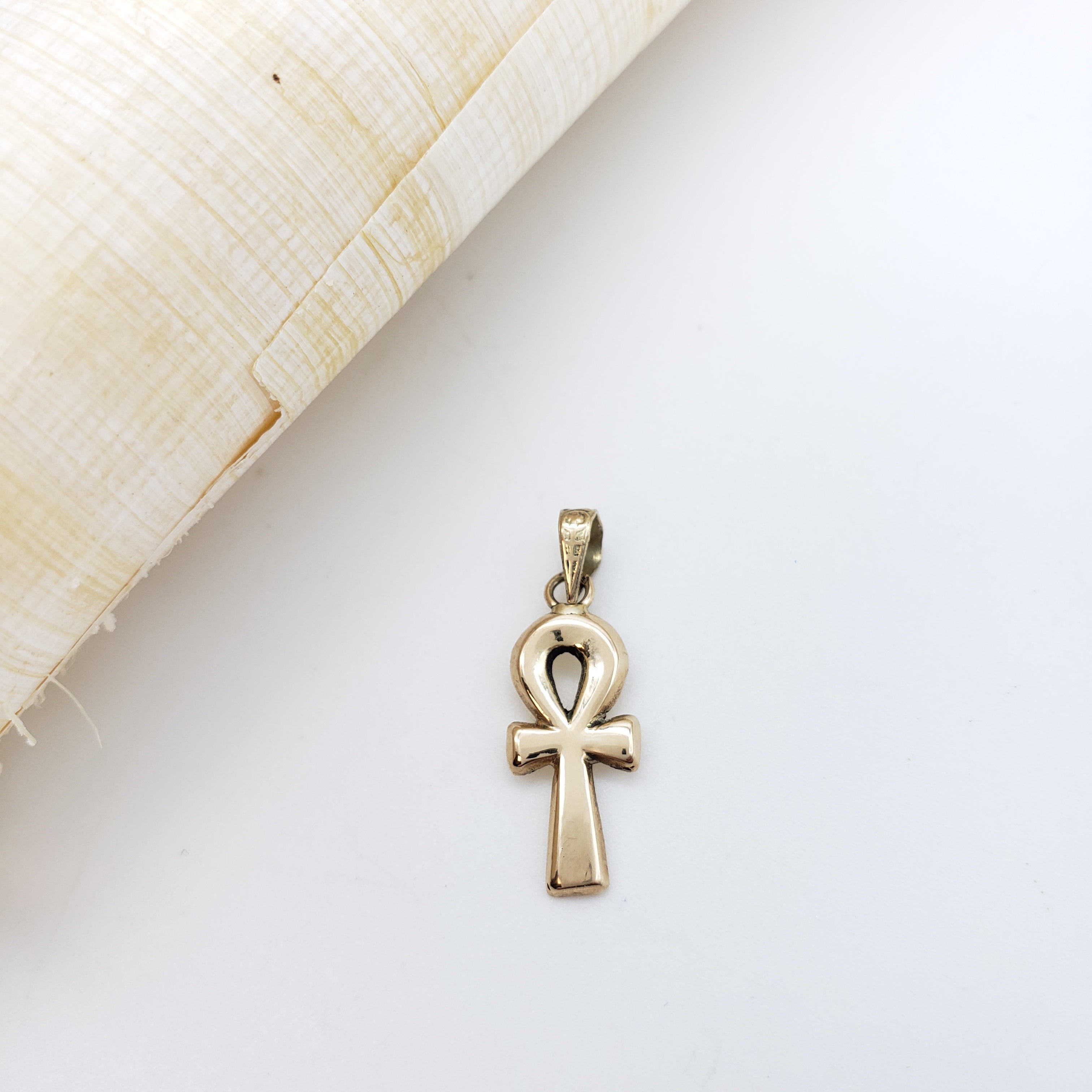 Gold ankh pendant on a white background