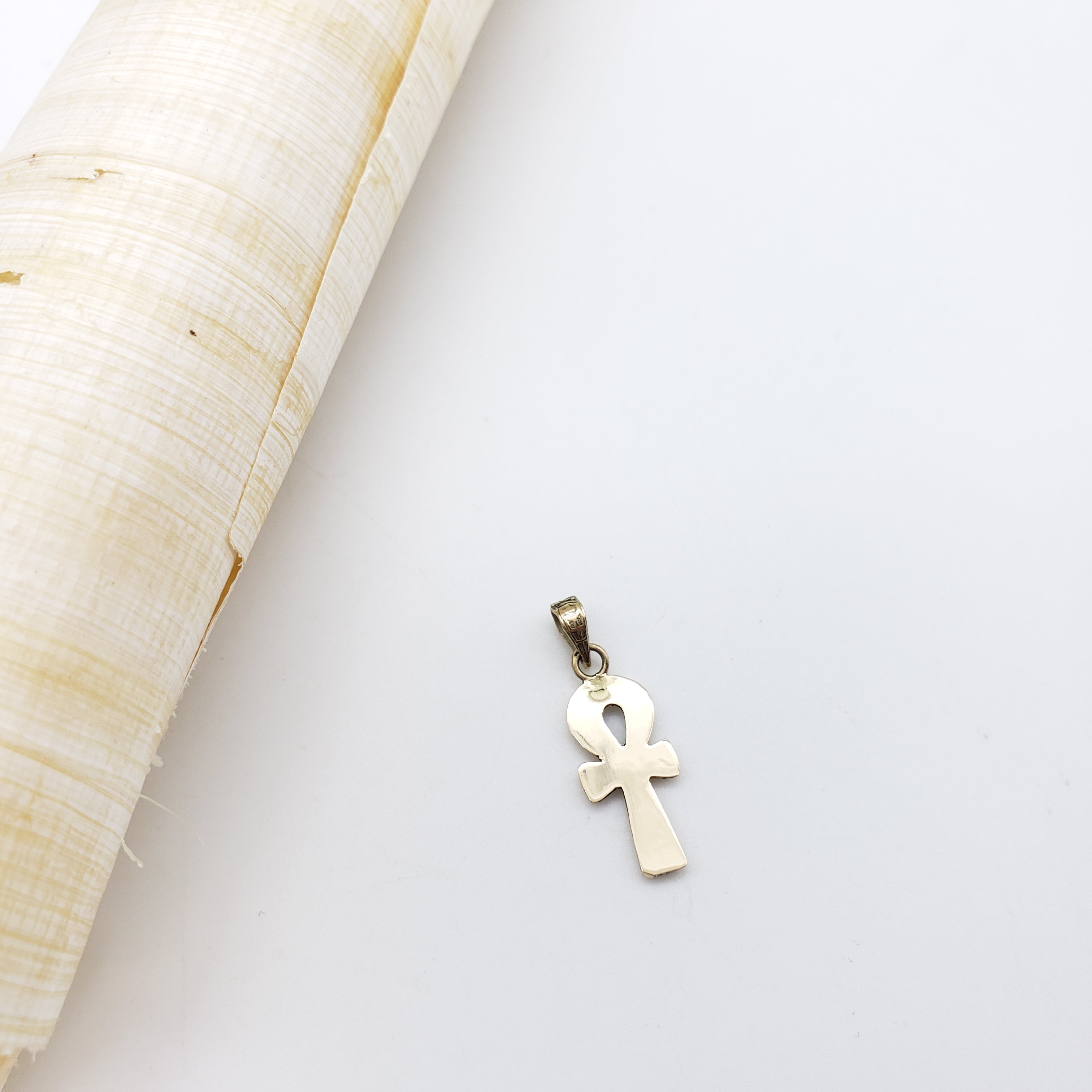Gold ankh pendant on a white background