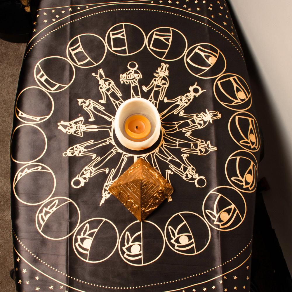 Decorative cloth with astrological symbols and a candle on a black background
