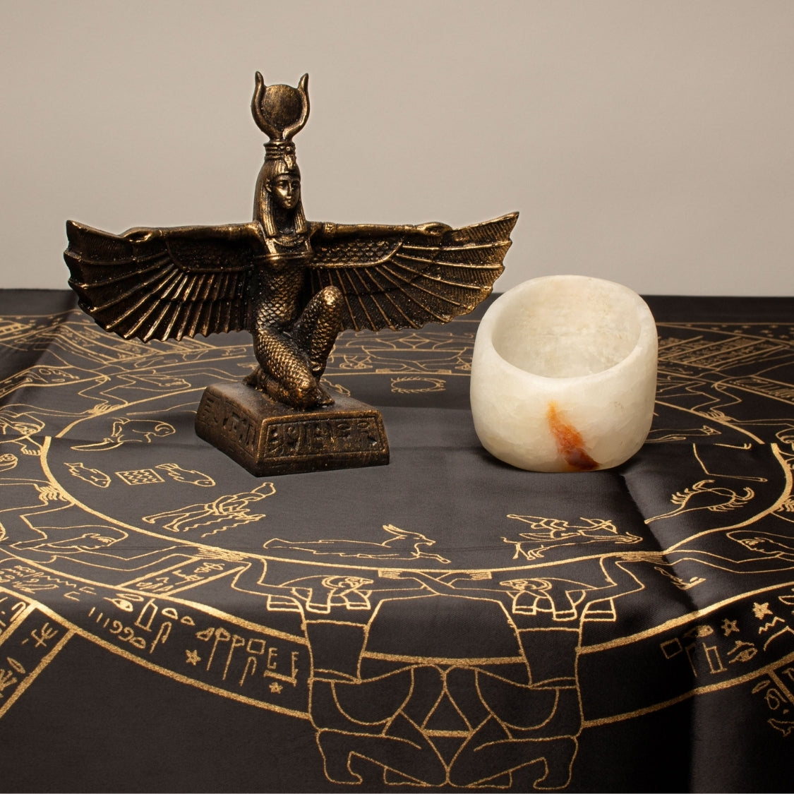 Bronze statue of Isis on a black cloth with gold designs