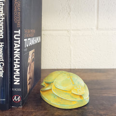 Two books titled 'Tutankhamun' and 'The Tomb of Tutankhamen' by Howard Carter on a wooden surface with a decorative wall piece.