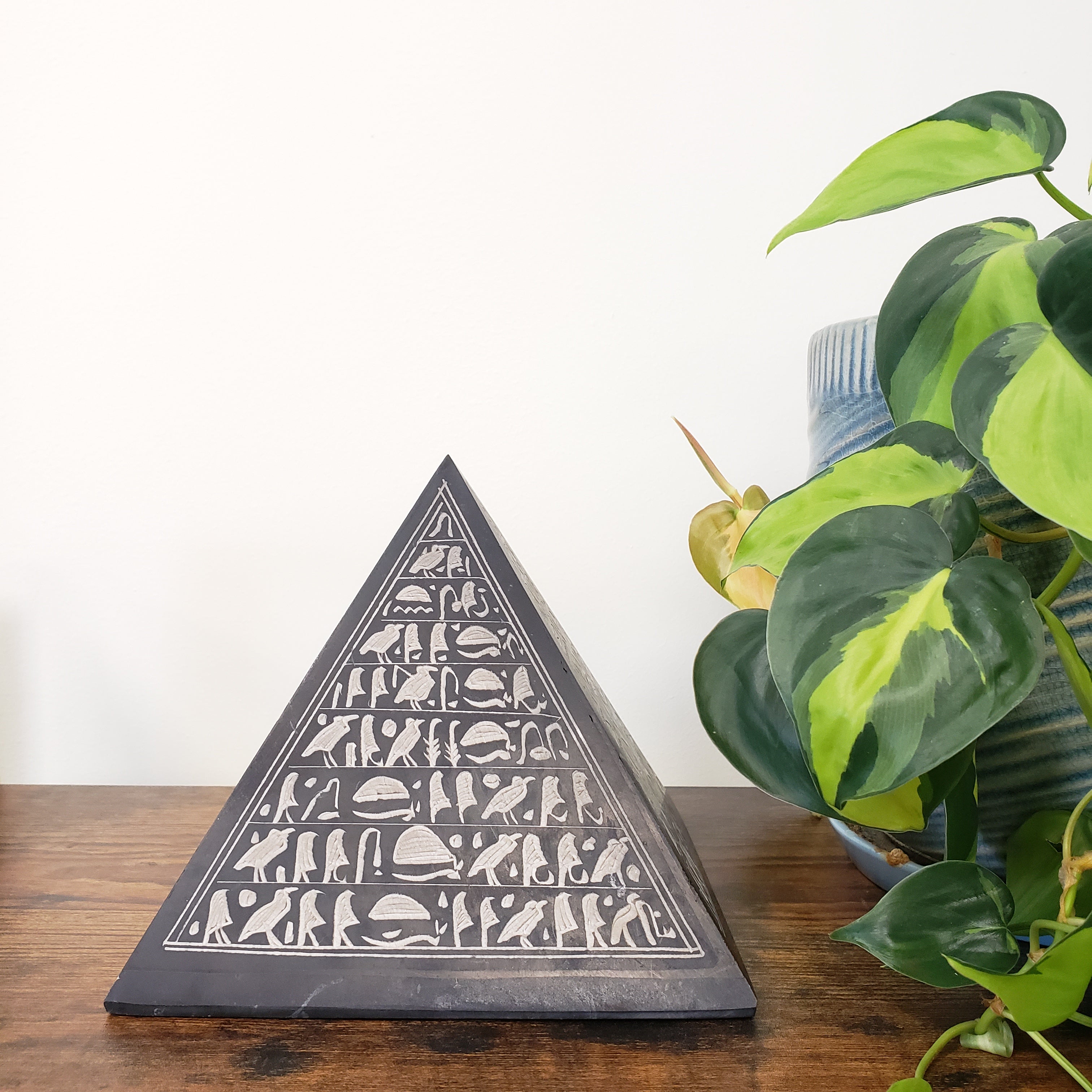 Decorative triangle wall art with a plant in the background