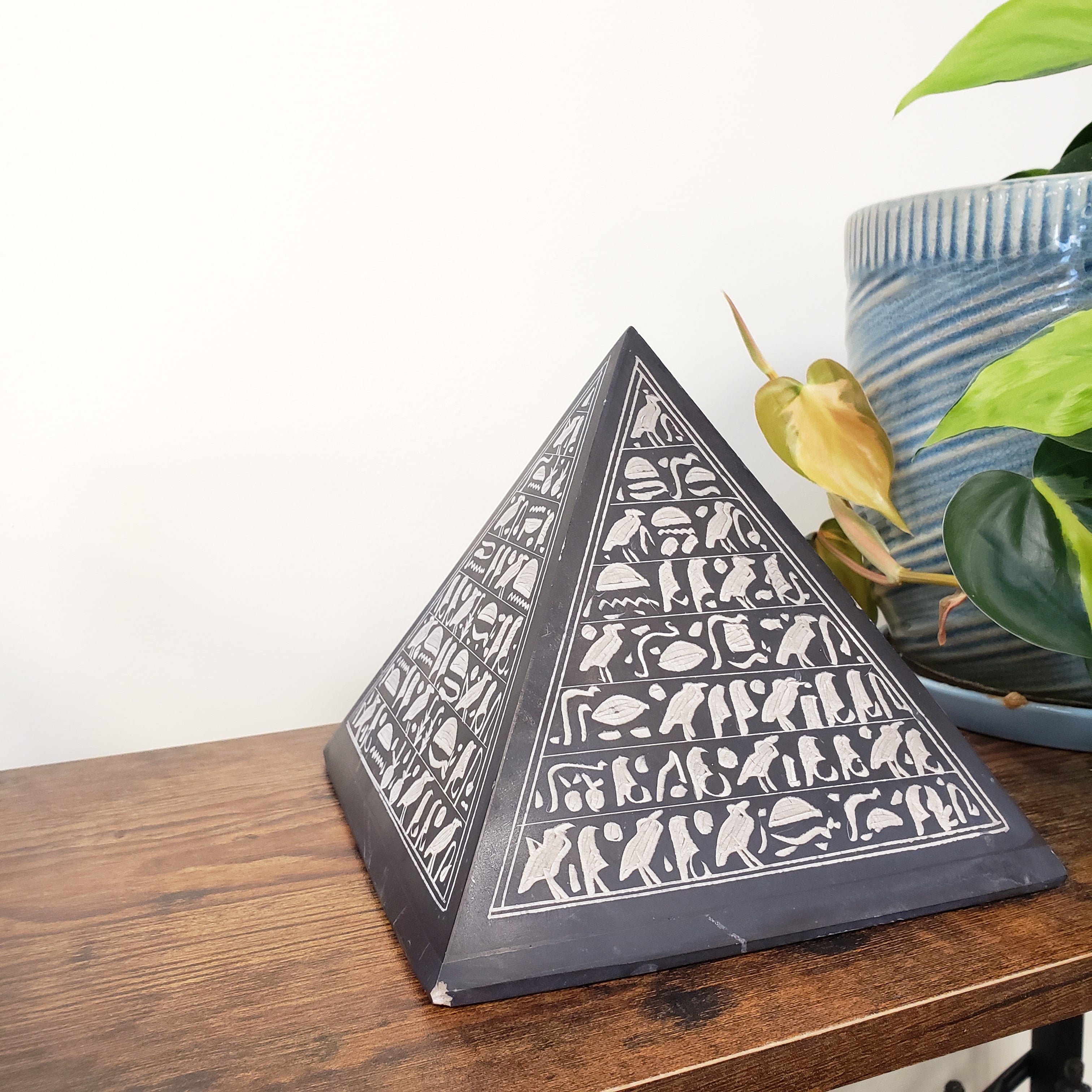 Decorative pyramid statue with white patterns on a wooden surface