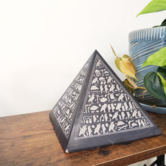 Decorative pyramid statue with white patterns on a wooden surface