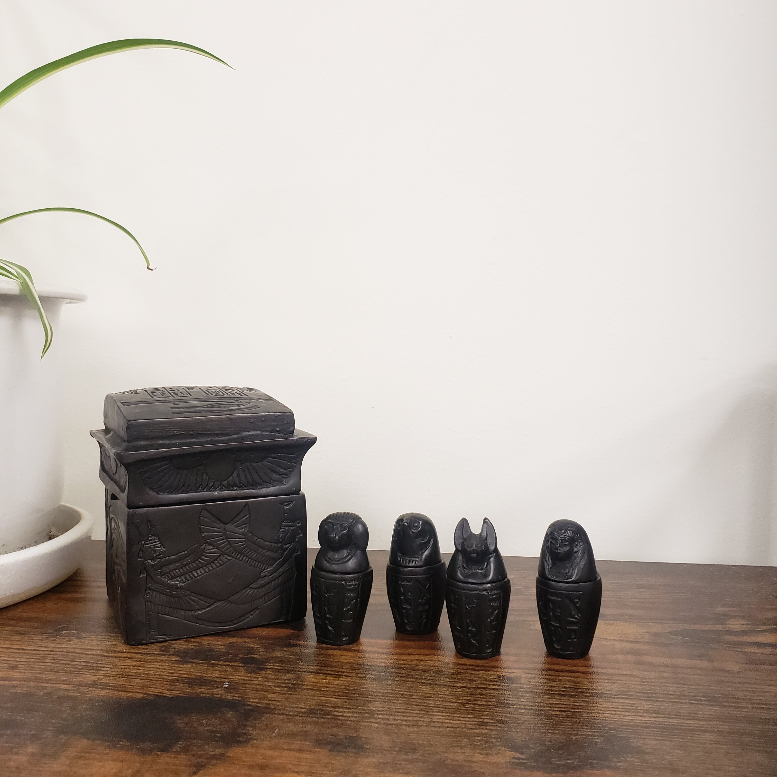 Set of black statues on a wooden surface with a white background