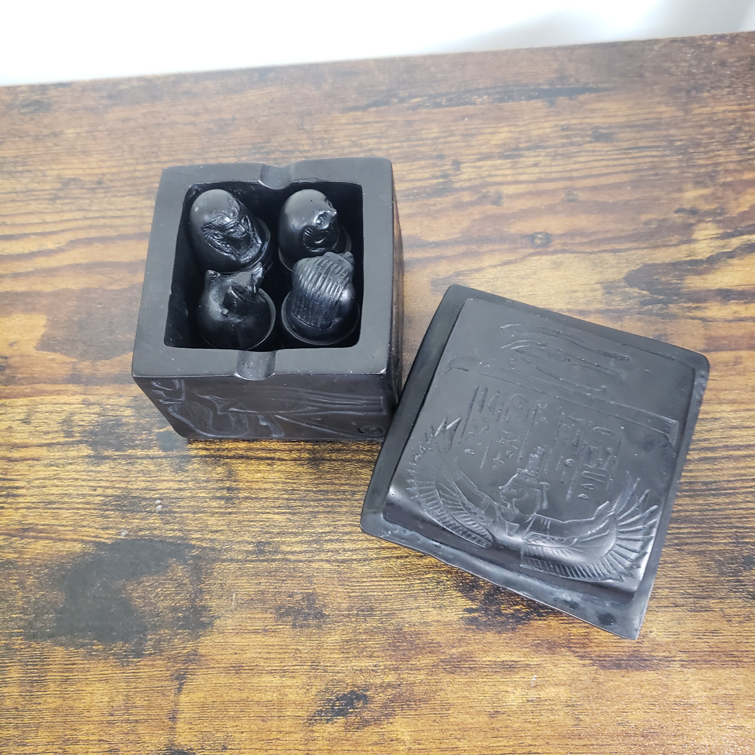 Black statues with engraved design on a wooden surface