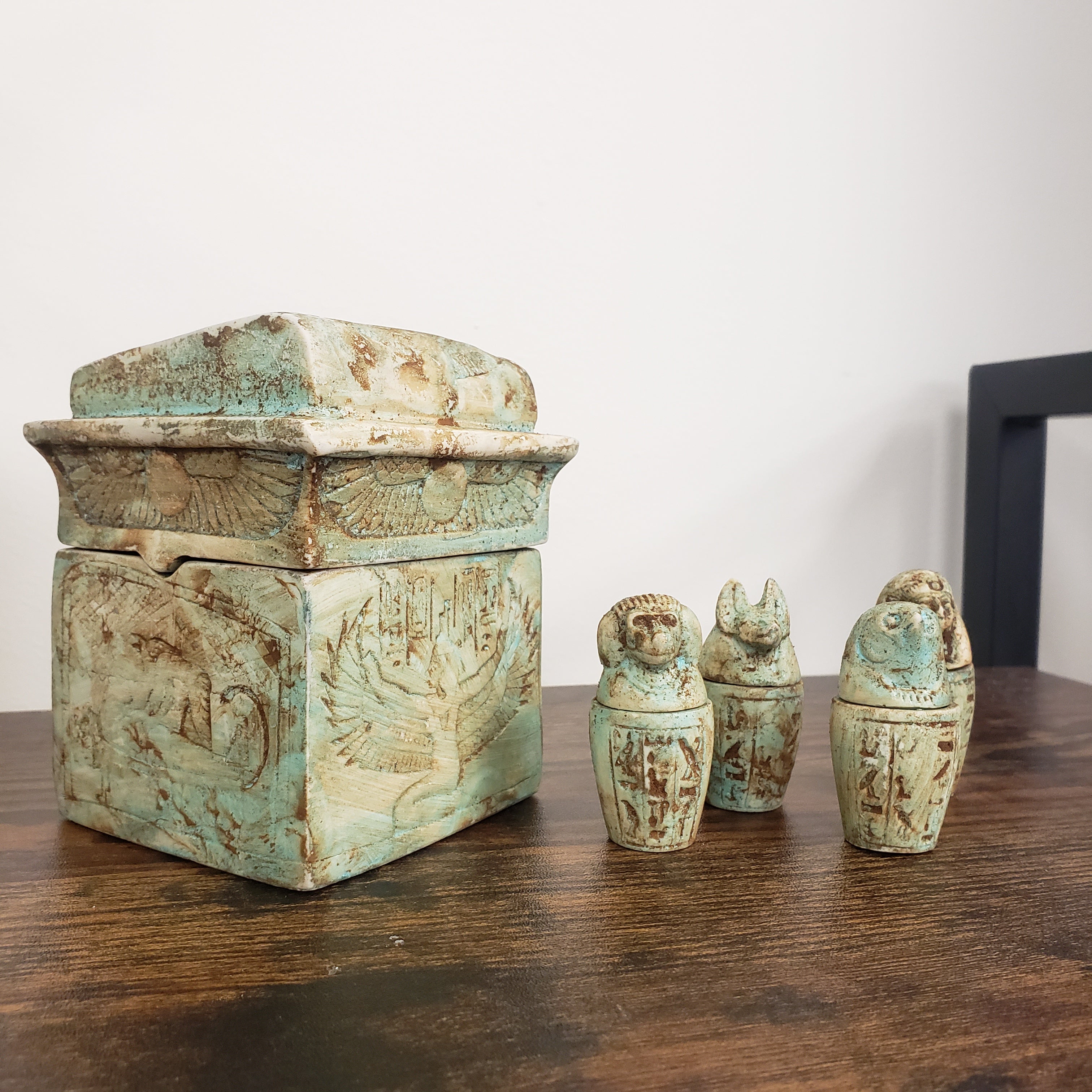 Decorative turquoise box with three small sculptures on a wooden surface