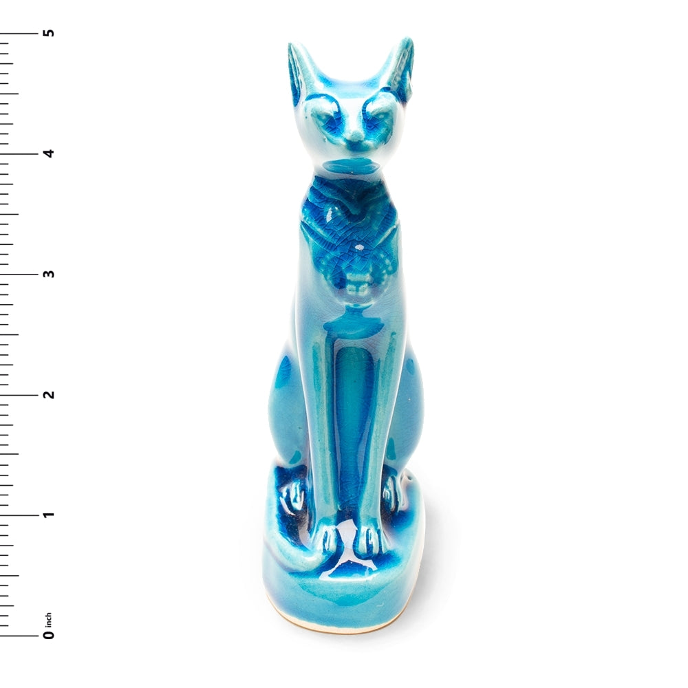 Blue ceramic cat figurine with a ruler for scale on a white background