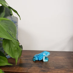 Blue decorative object on a wooden surface with green leaves in the foreground