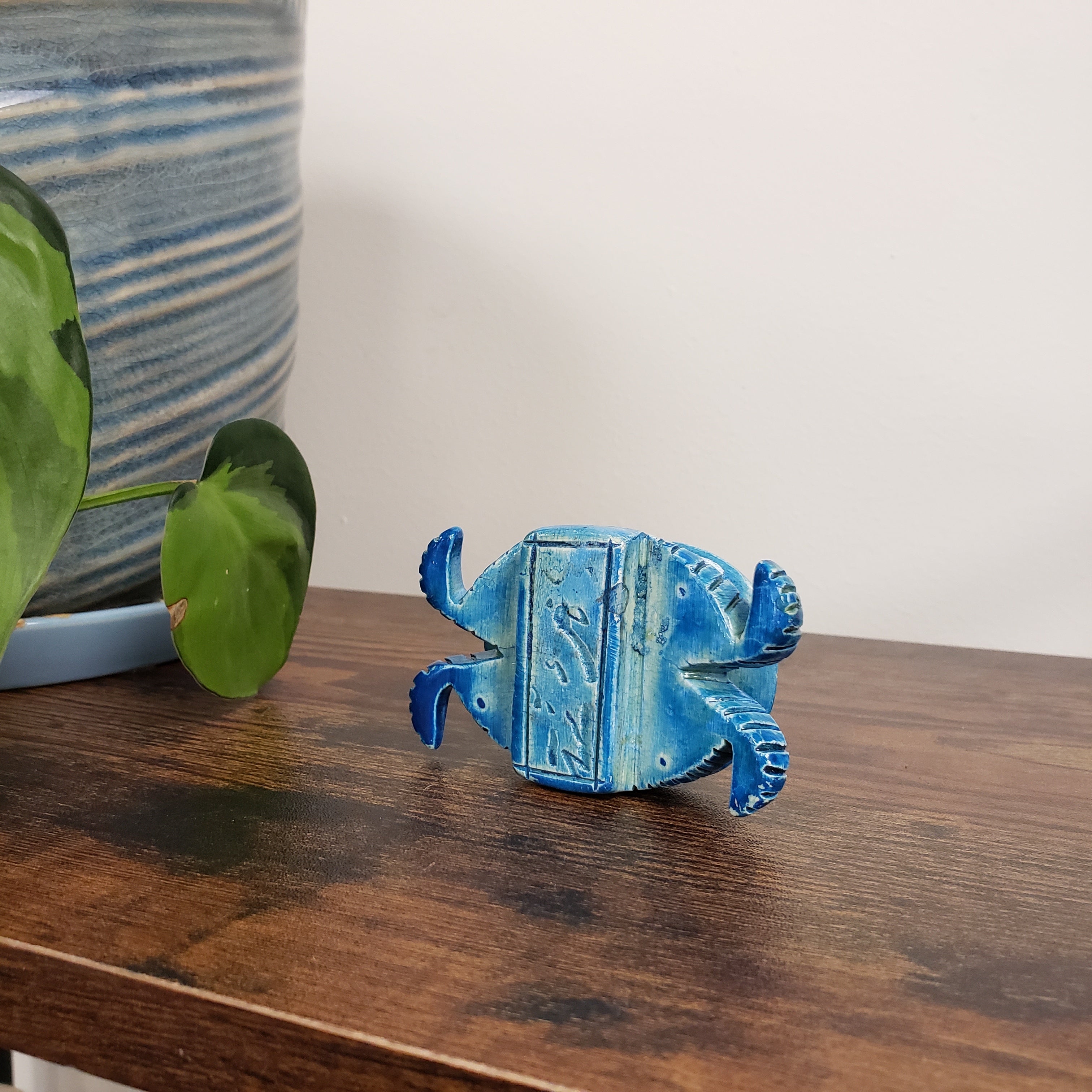 Blue decorative item on a wooden surface with a plant in the foreground
