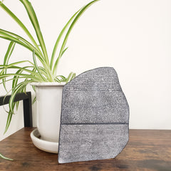 Textured gray mat on a white surface with a plant and wooden edge.
