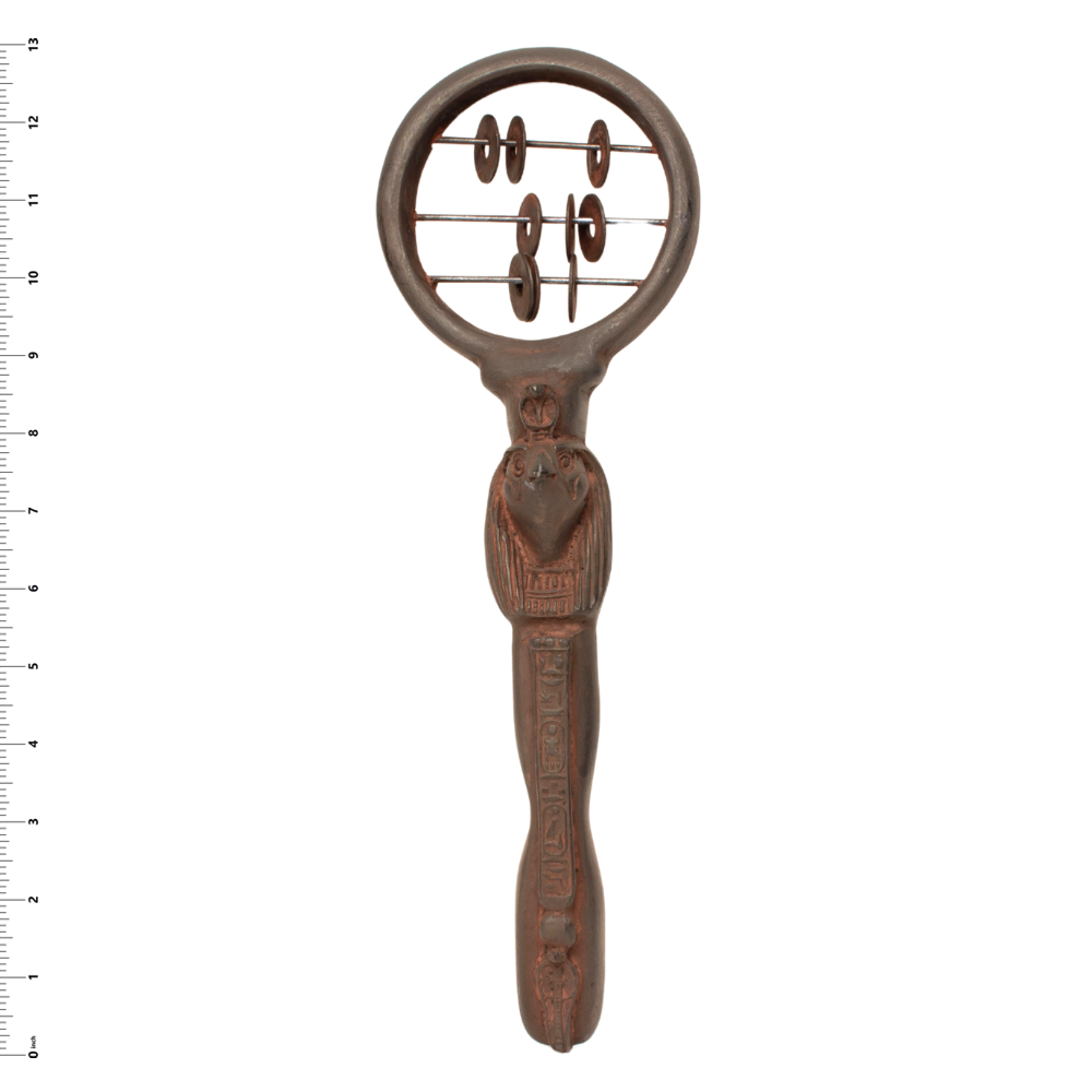 A carved wooden hand held circular frame and a detailed handle featuring a central figure, shown against a white background with a ruler on the left side.