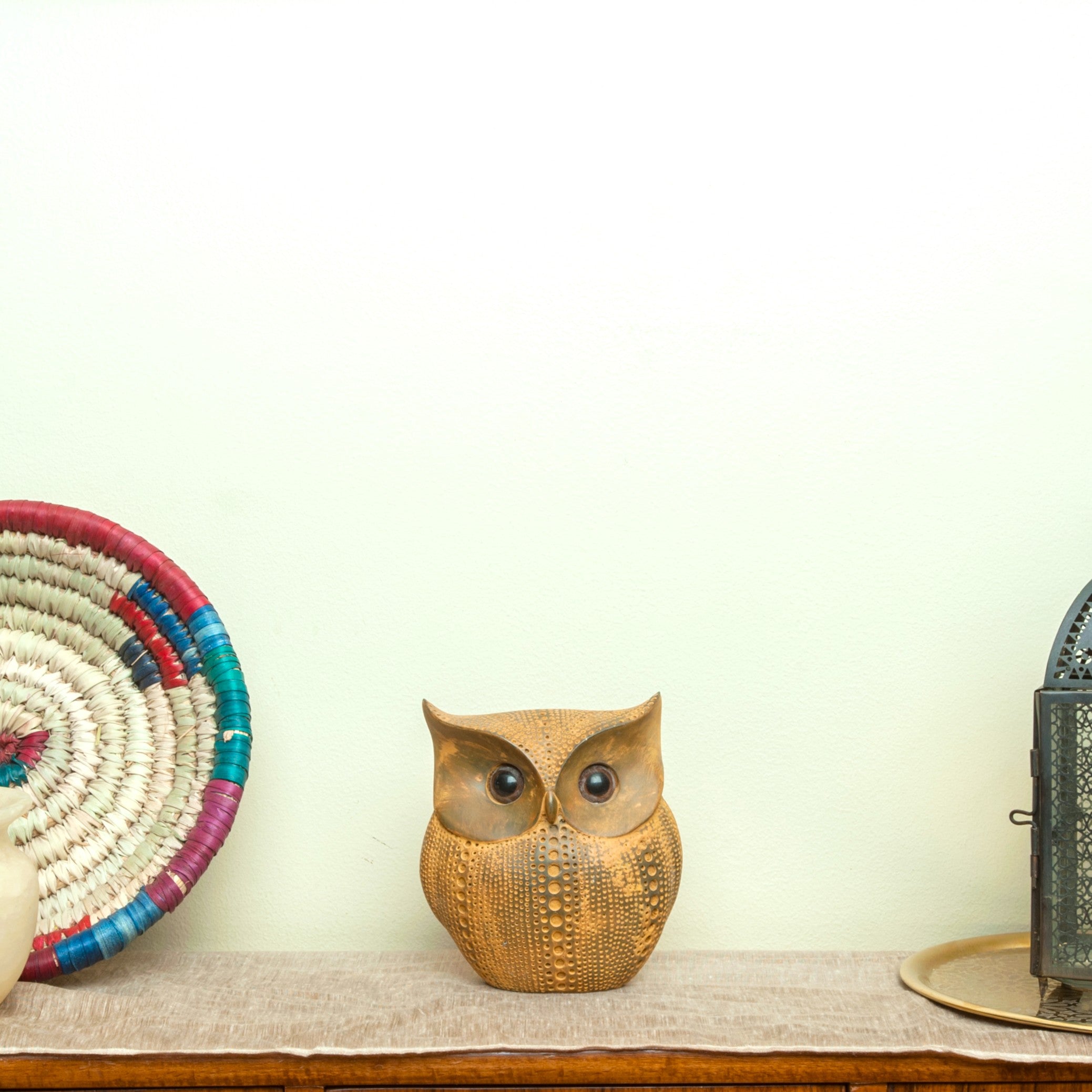 Decorative owl figurine on a shelf with a plain background