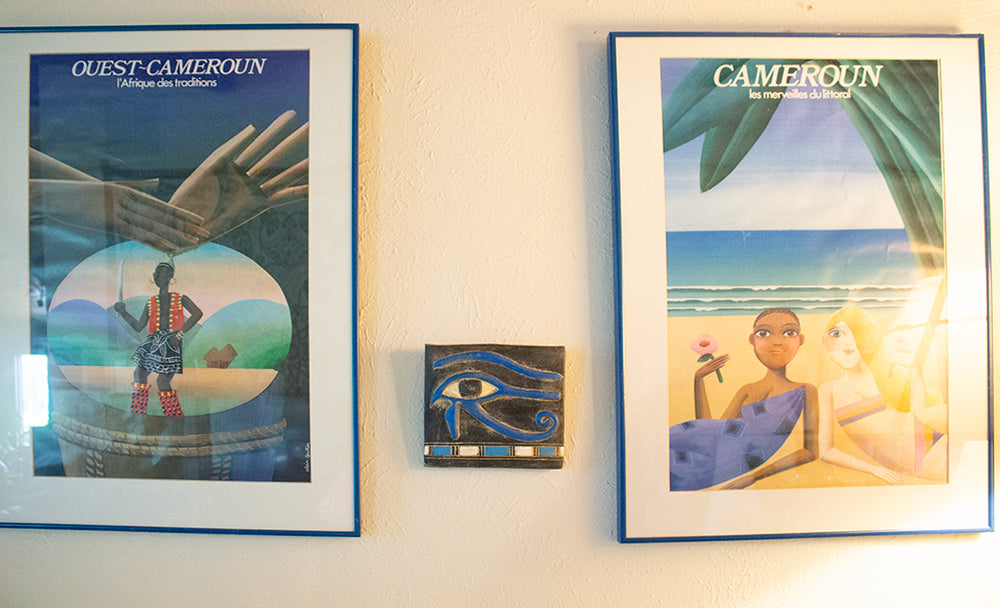 Two framed posters on a wall with a decorative item between them.