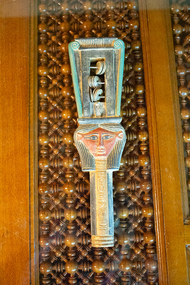 Decorative metal object with a face design on a textured background