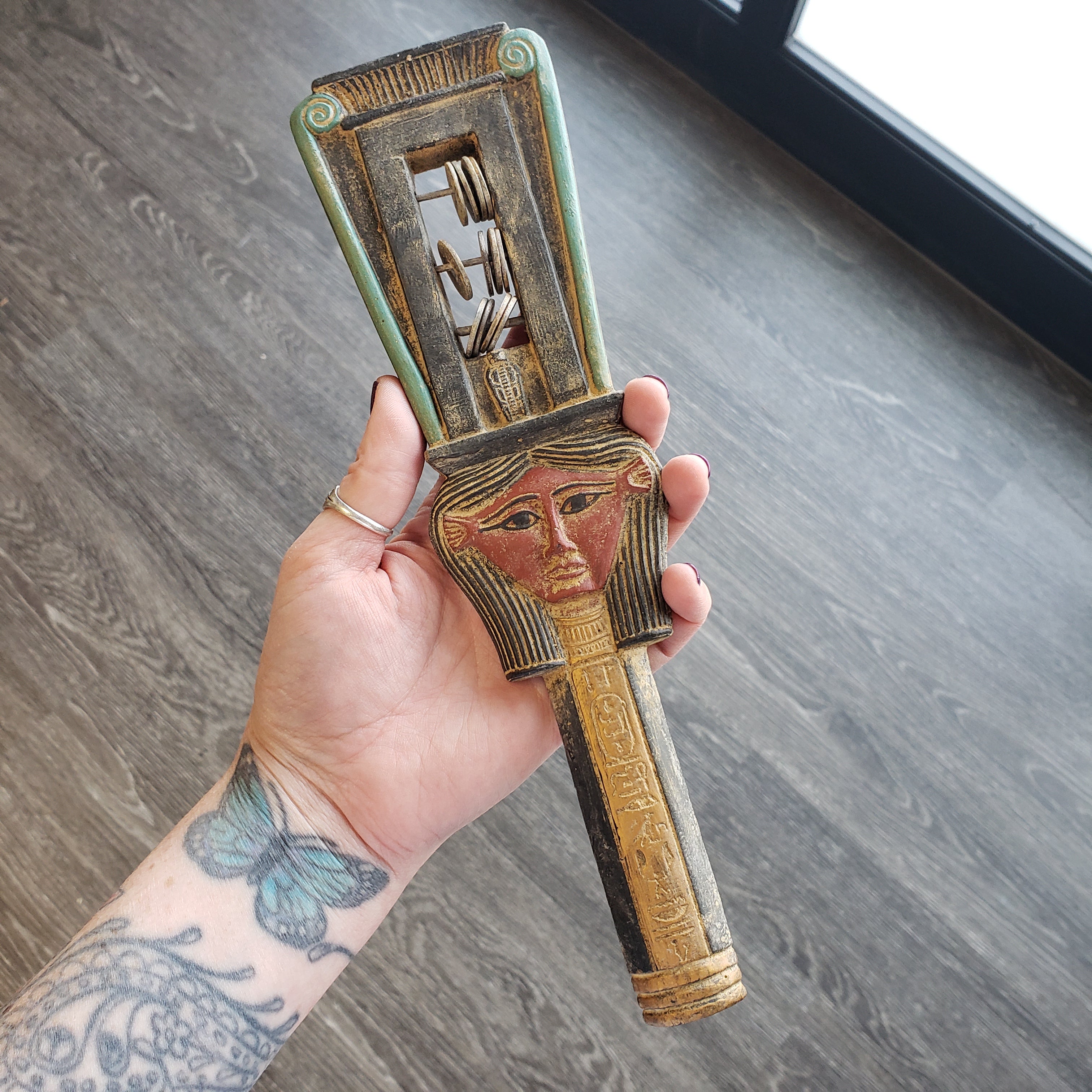 Hand holding a decorative object with intricate designs on a wooden surface