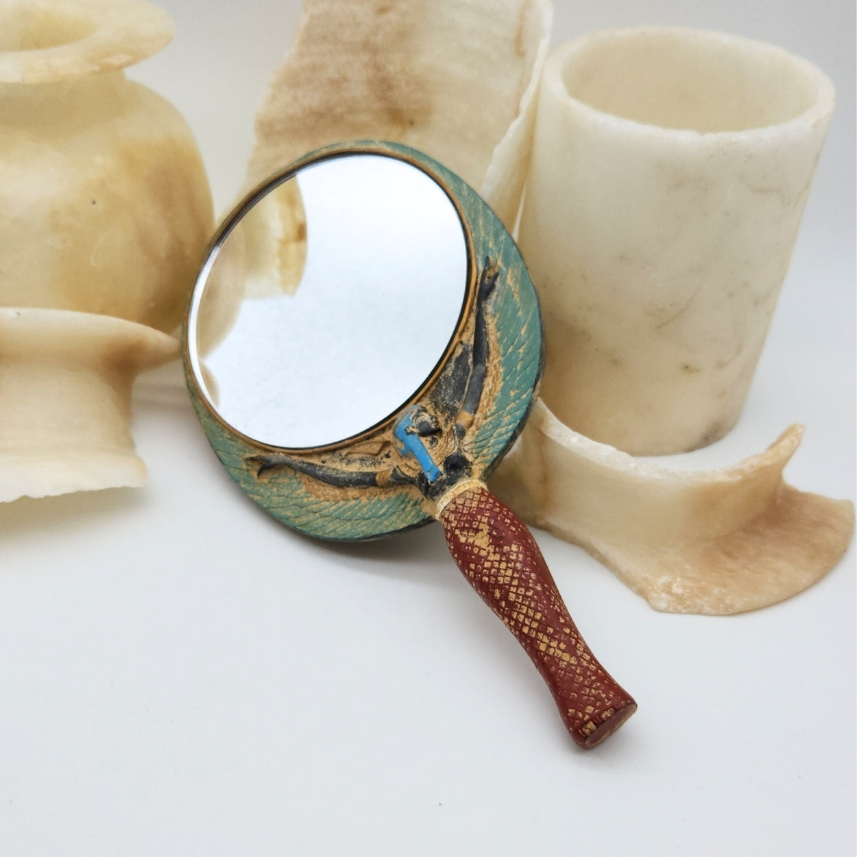 Handheld mirror with decorative handle on a white background