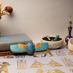Decorative items including a blue scarab, book, and bowl on a surface with hieroglyphics.