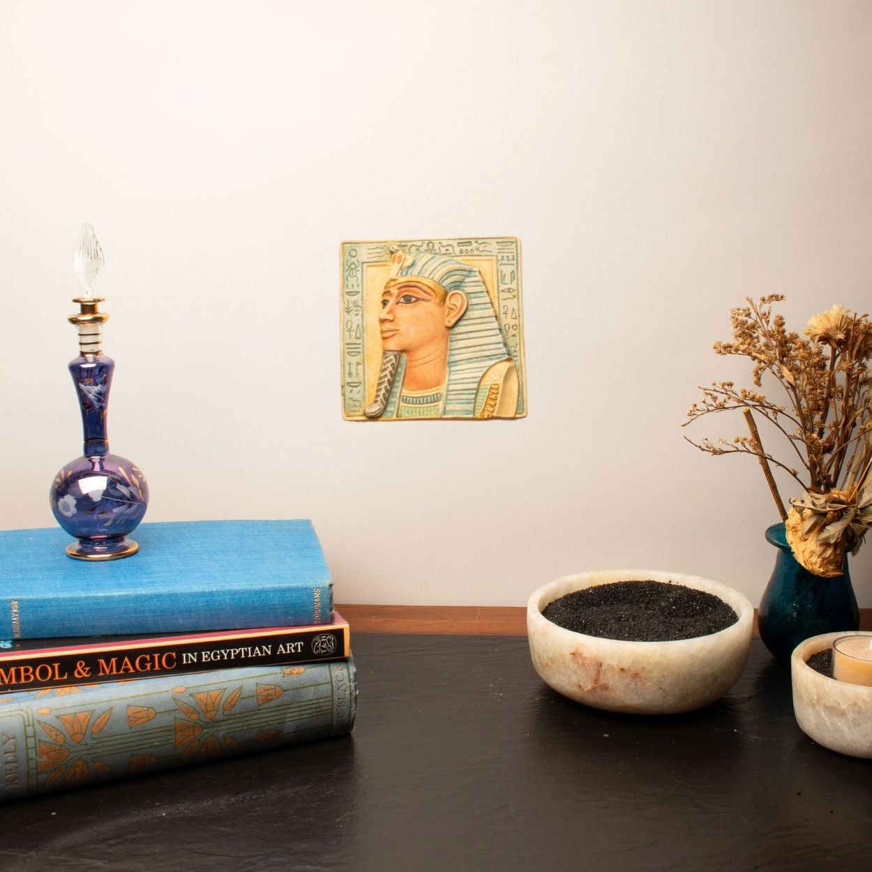 Decorative setup with books, a candle, and a small statue on a table.