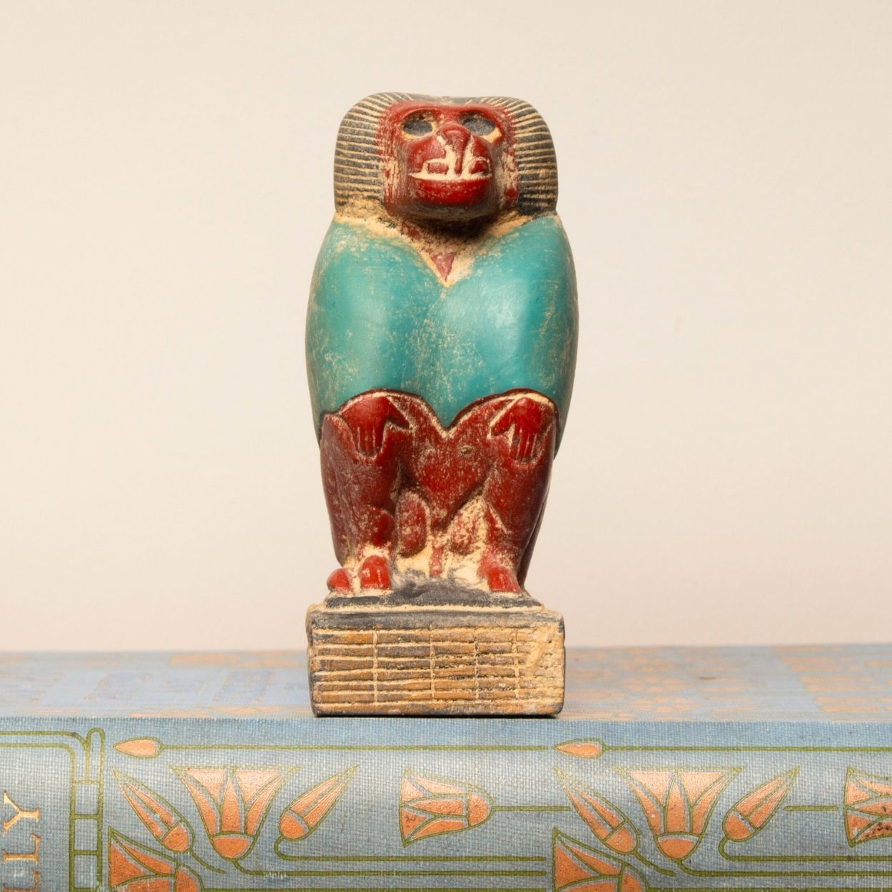 Decorative item of a baboon on a decorative base against a beige background