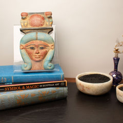 Decorative items including a bust, books, and bowls on a surface.