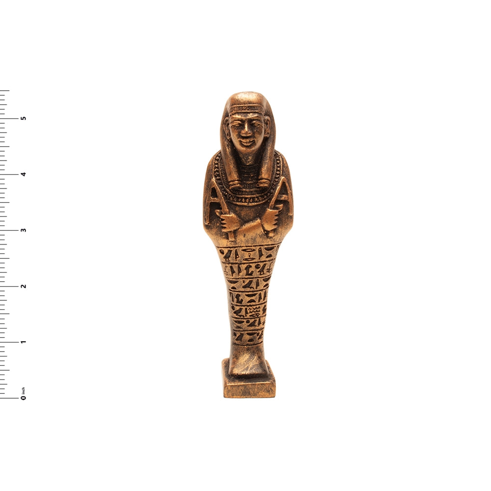 Bronze-colored Egyptian-style statuette on a white background with a ruler for scale.