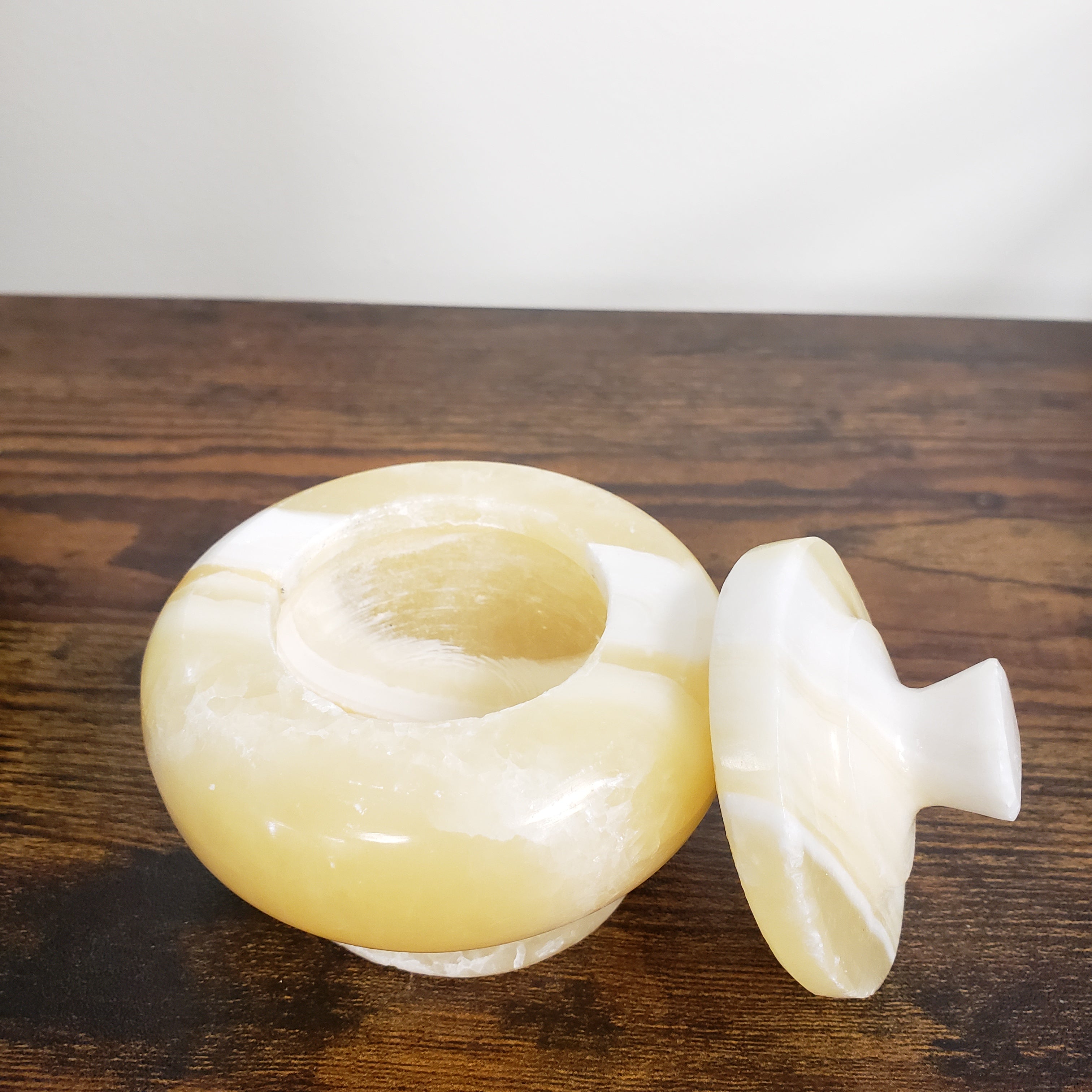 Decorative alabaster jar with a white and beige design on a wooden surface.