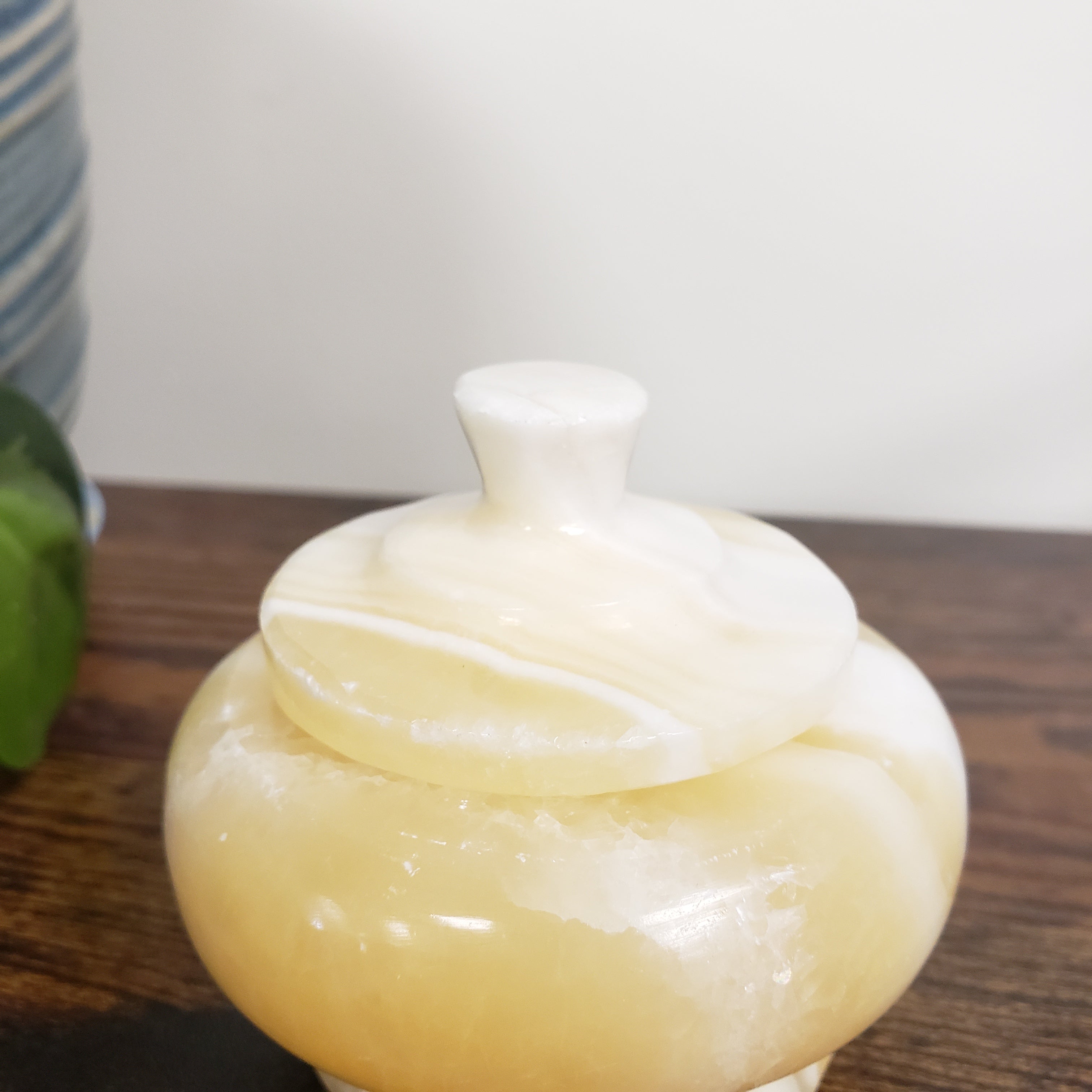 Close-up of a white ceramic vase on a wooden surface with a blurred background