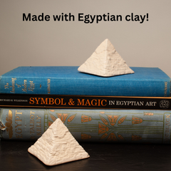 Two small white pyramid-shaped clay objects displayed on top of and in front of two decorative books, with the text 'Made with Egyptian clay!' above the scene.
