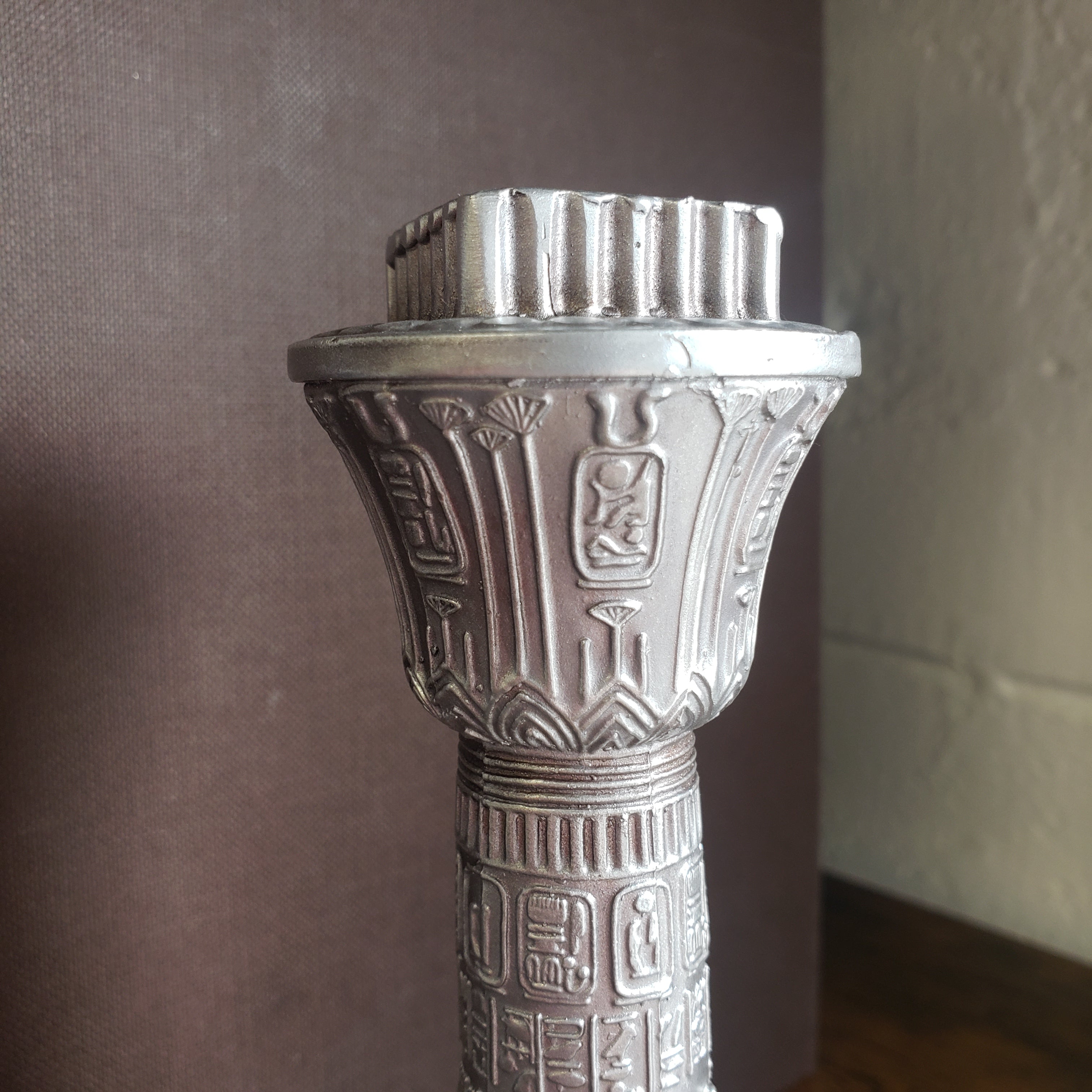 Decorative silver object with intricate designs on a dark surface