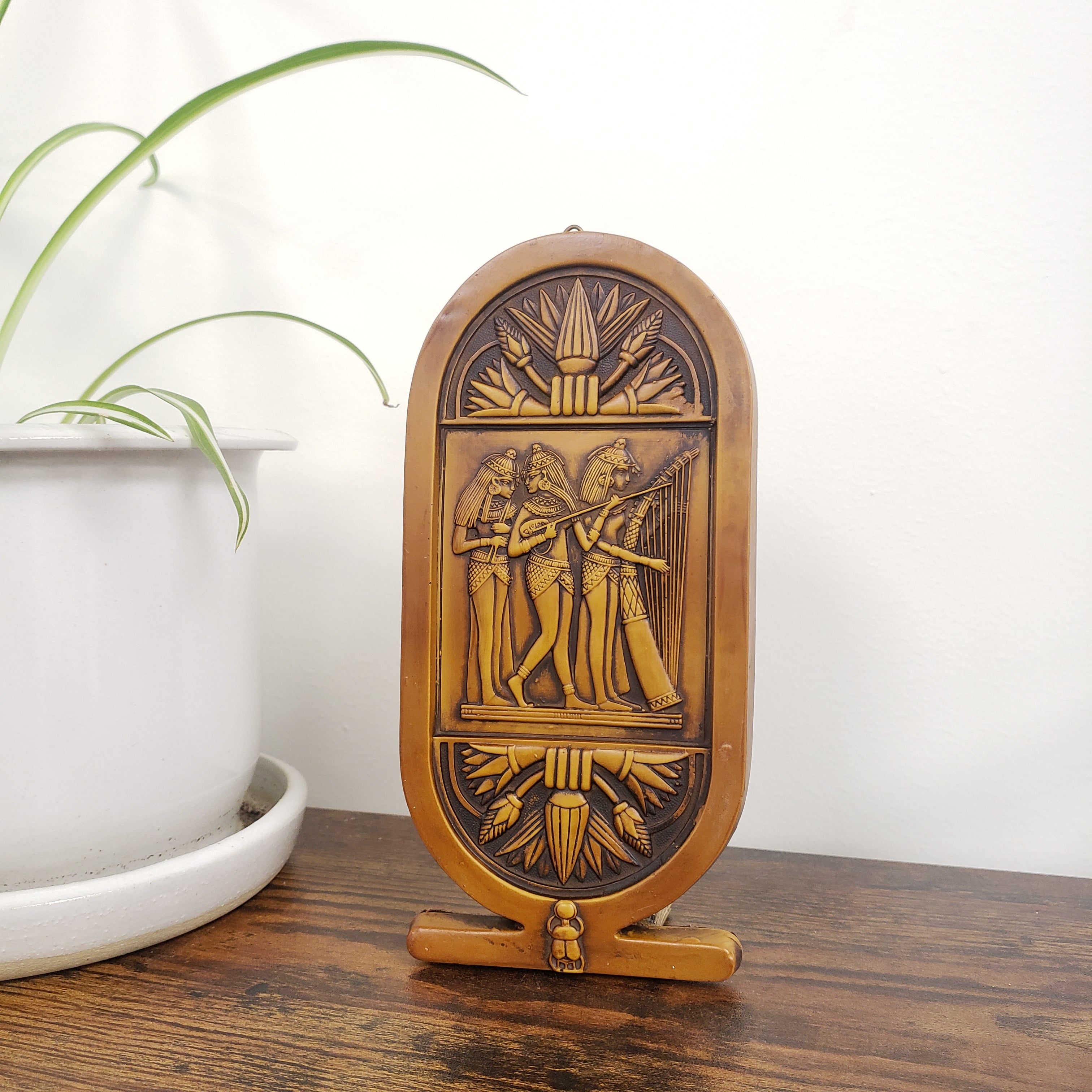 Decorative plaque with intricate carvings on a white and wooden background