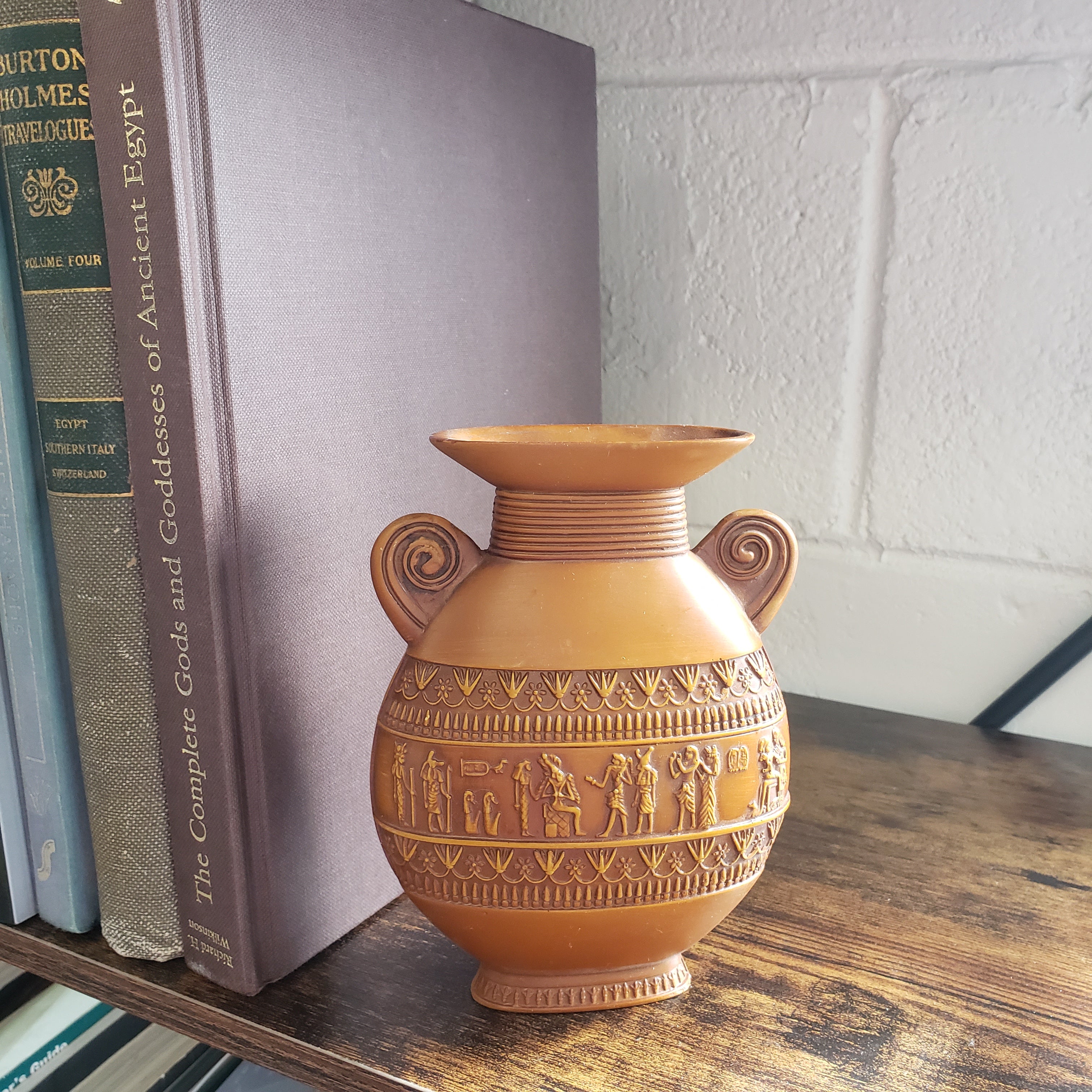 Decorative brown vase with intricate patterns on top of books