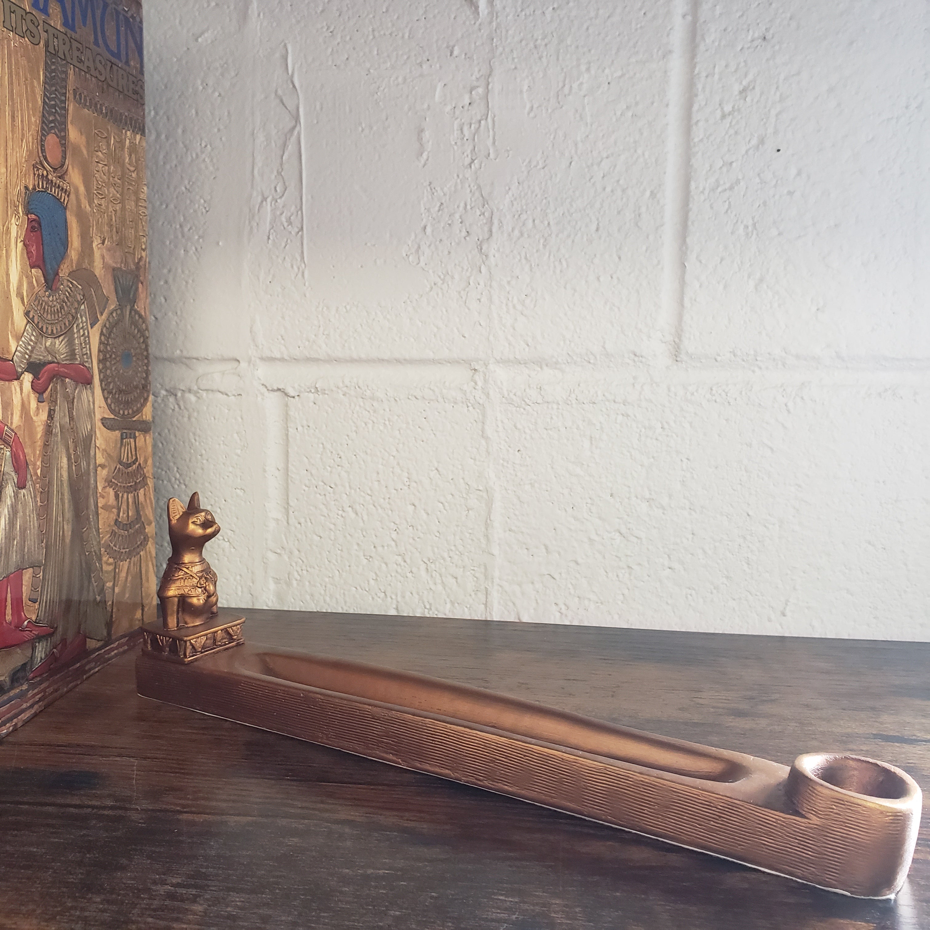 incense holder with decorative cat design against a white brick wall