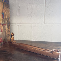 incense holder with decorative cat design against a white brick wall
