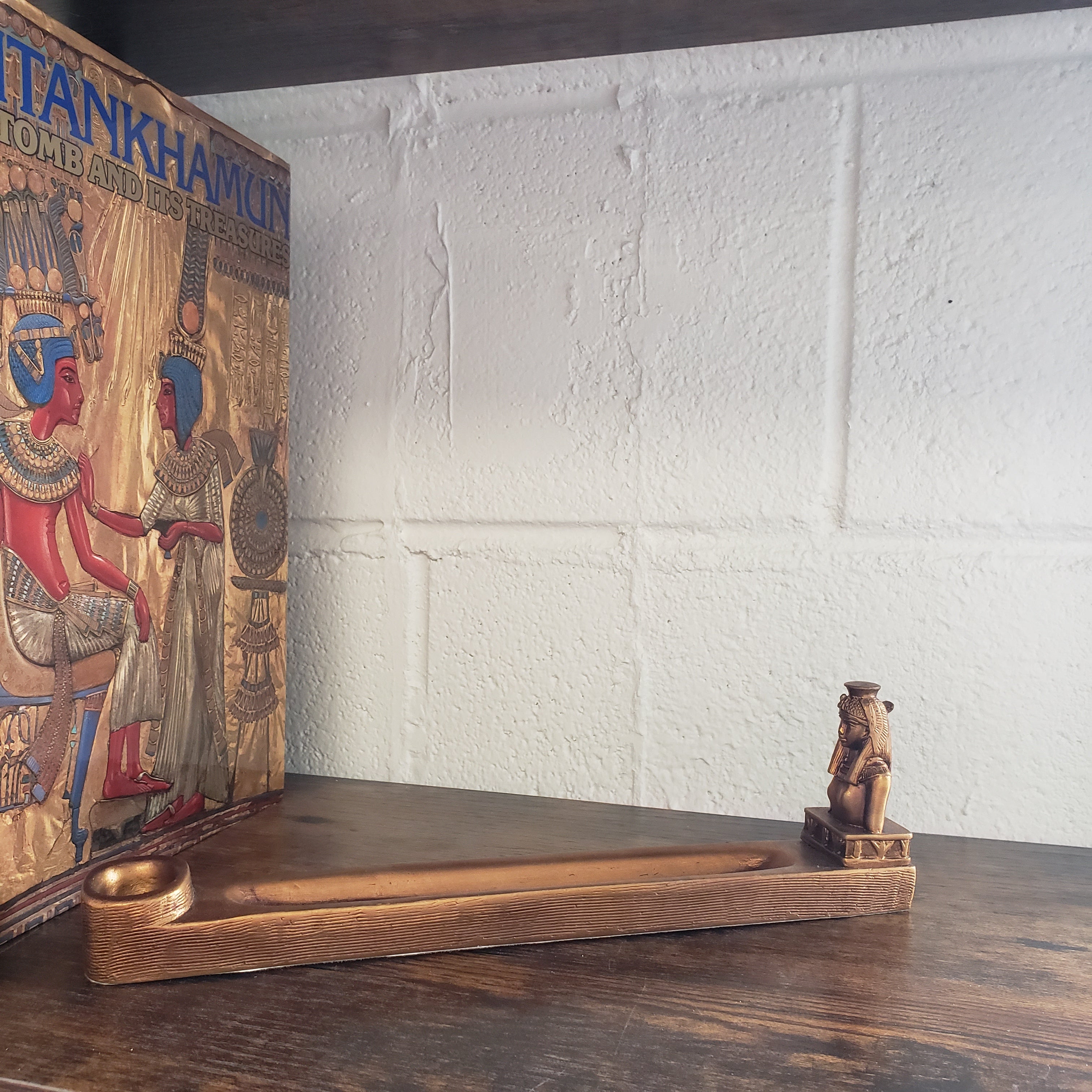 Decorative Incense holder with intricate designs on a wooden surface against a white brick wall.