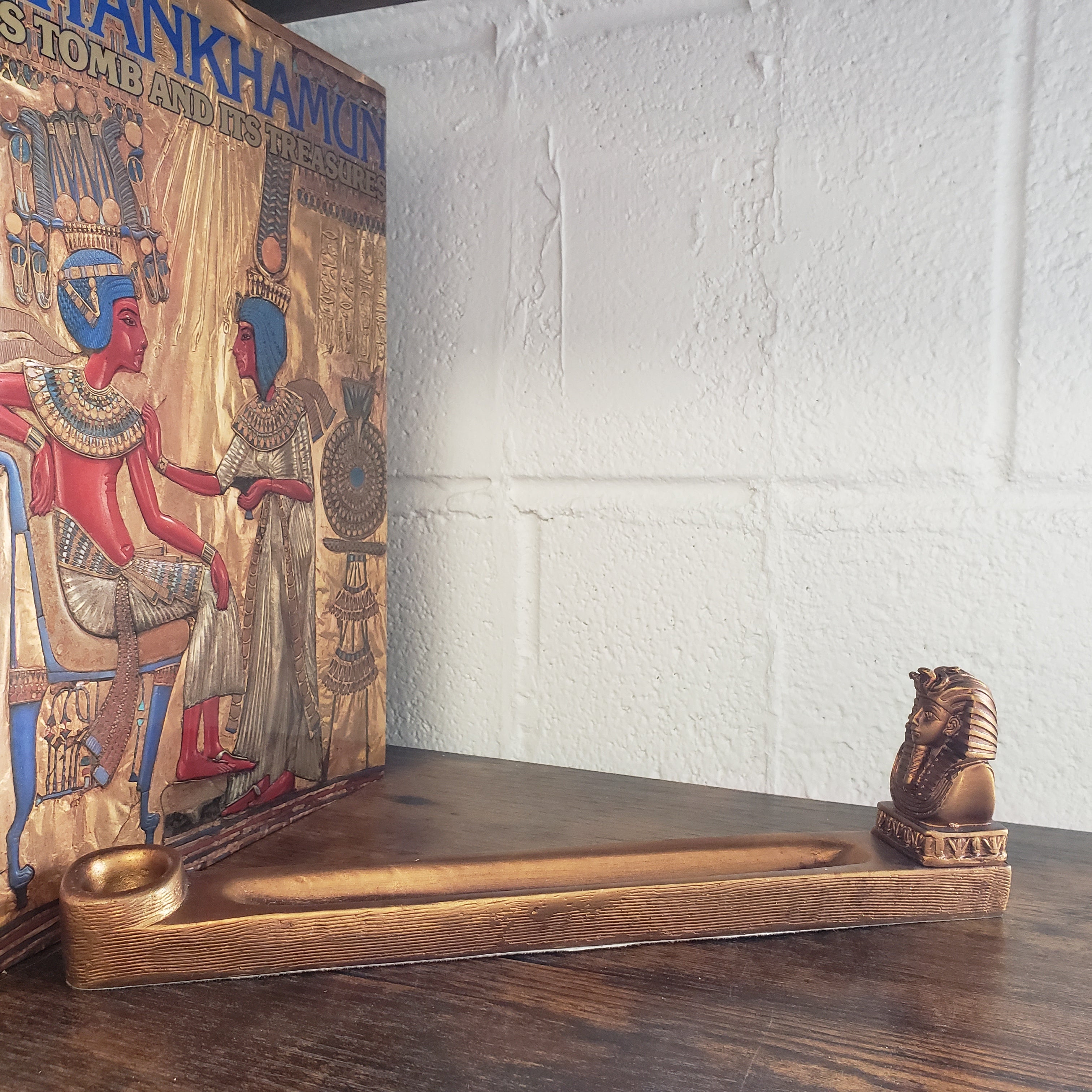 Decorative incense holder with intricate carvings against a white brick wall. 
