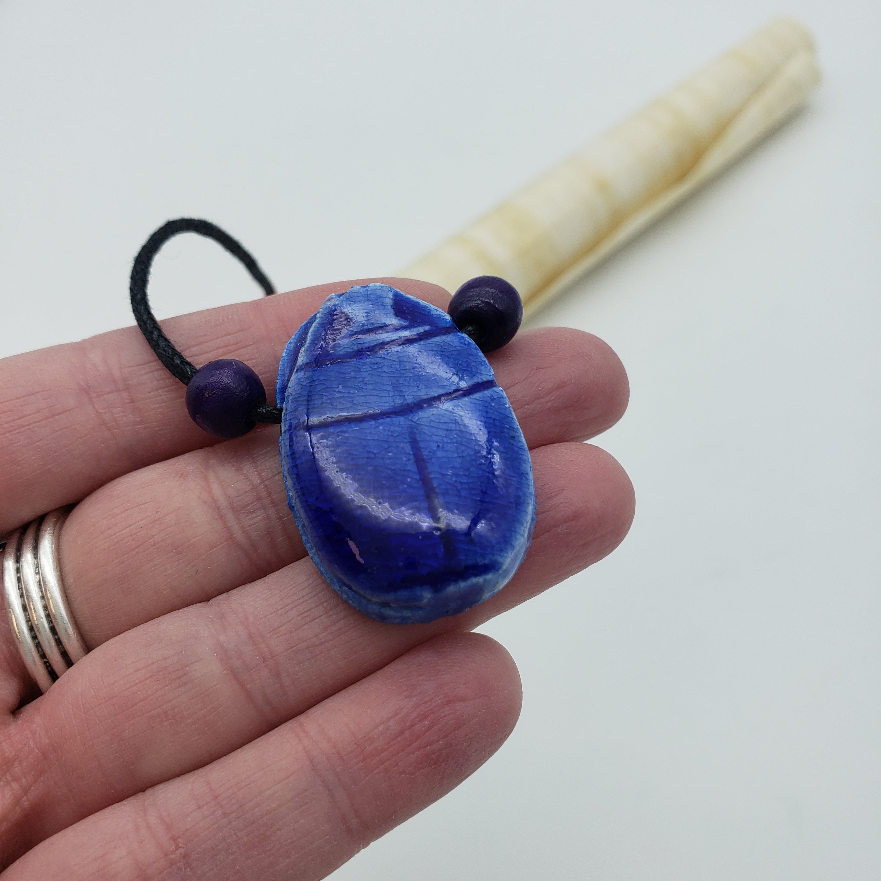 Hand holding a blue keychain with a white background
