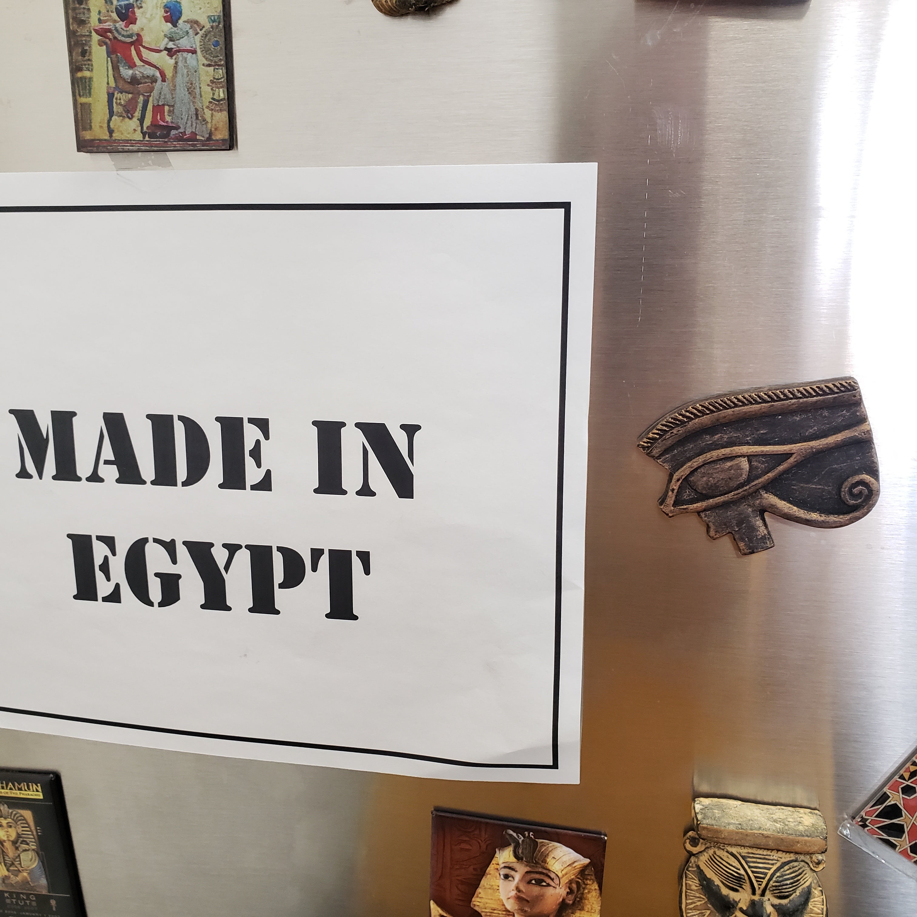 Framed poster with 'MADE IN EGYPT' text on a wall with decorative items.